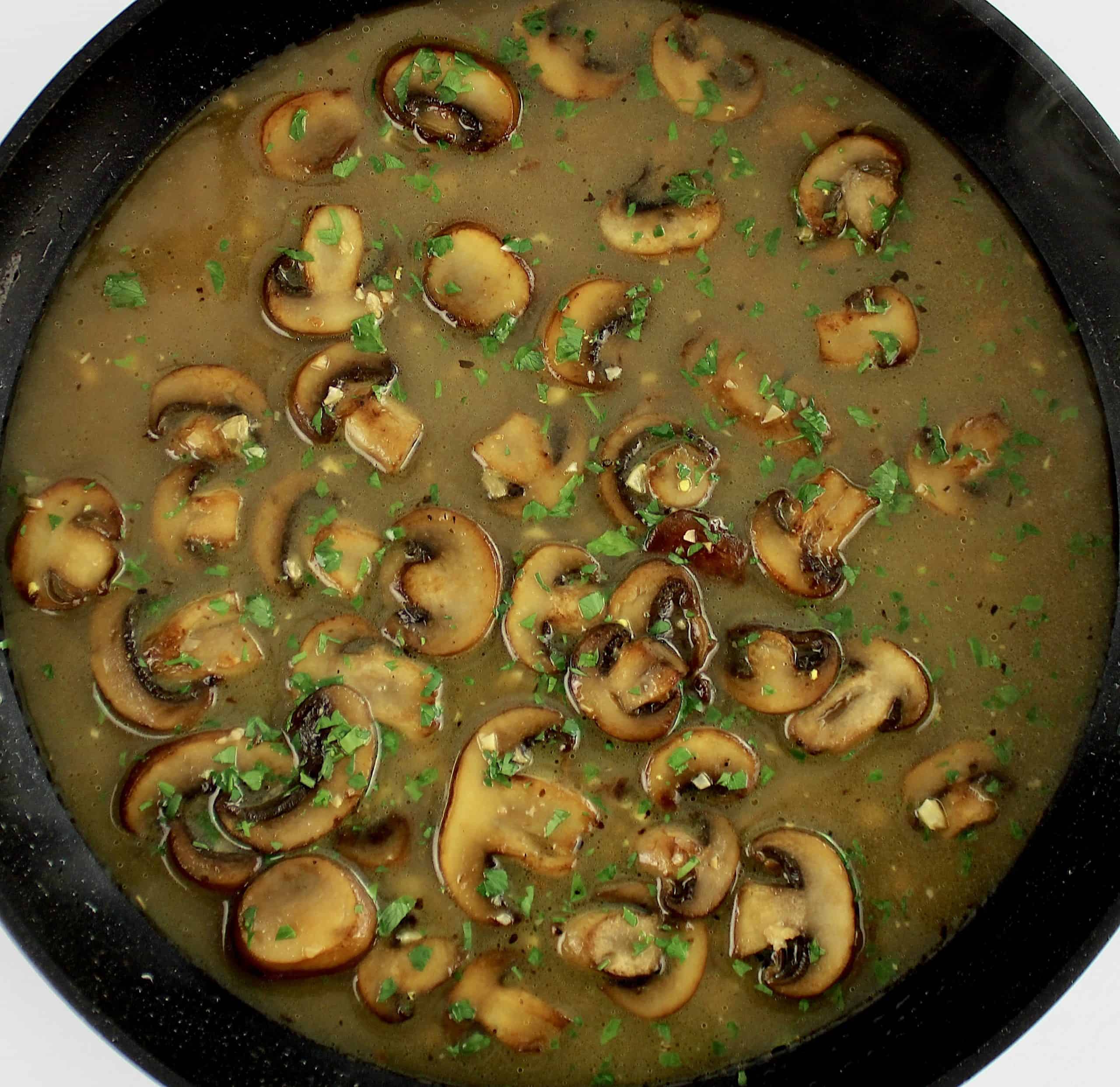 marsala wine sauce in skillet with sliced mushrooms and chopped parsley