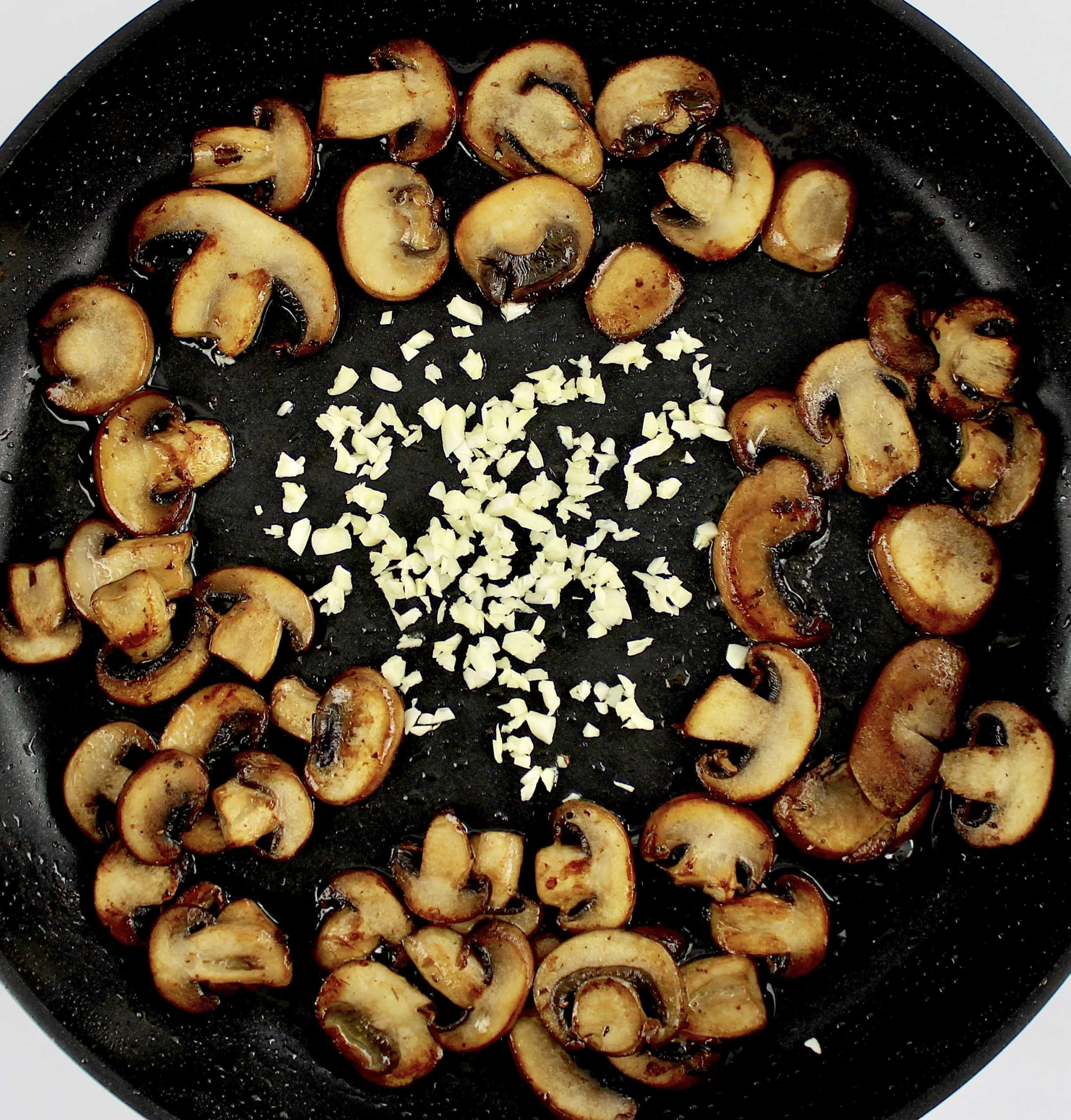 sauteed mushrooms in skillet with minced garlic in the center