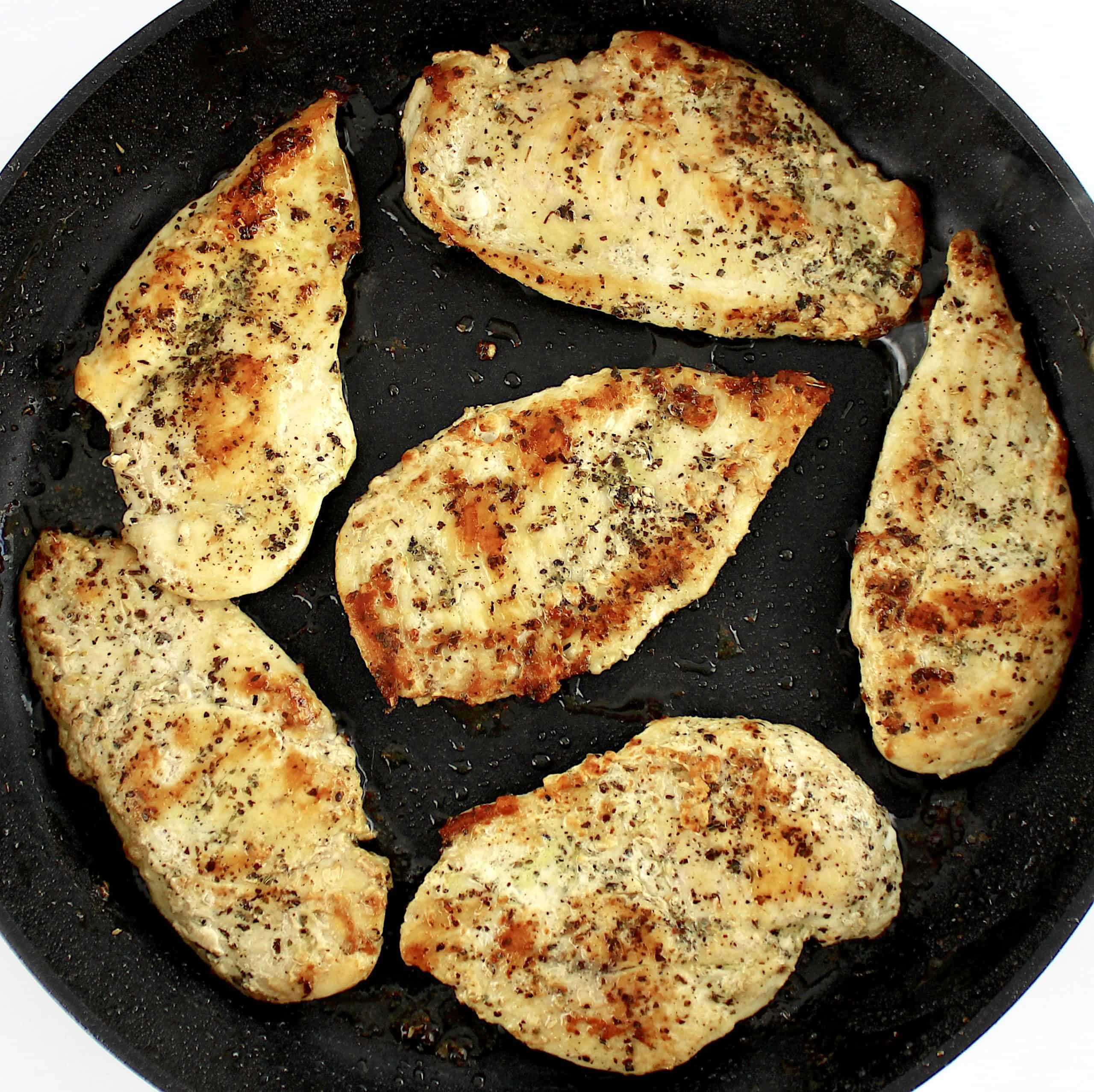 6 cooked chicken breasts with spices on top in skillet