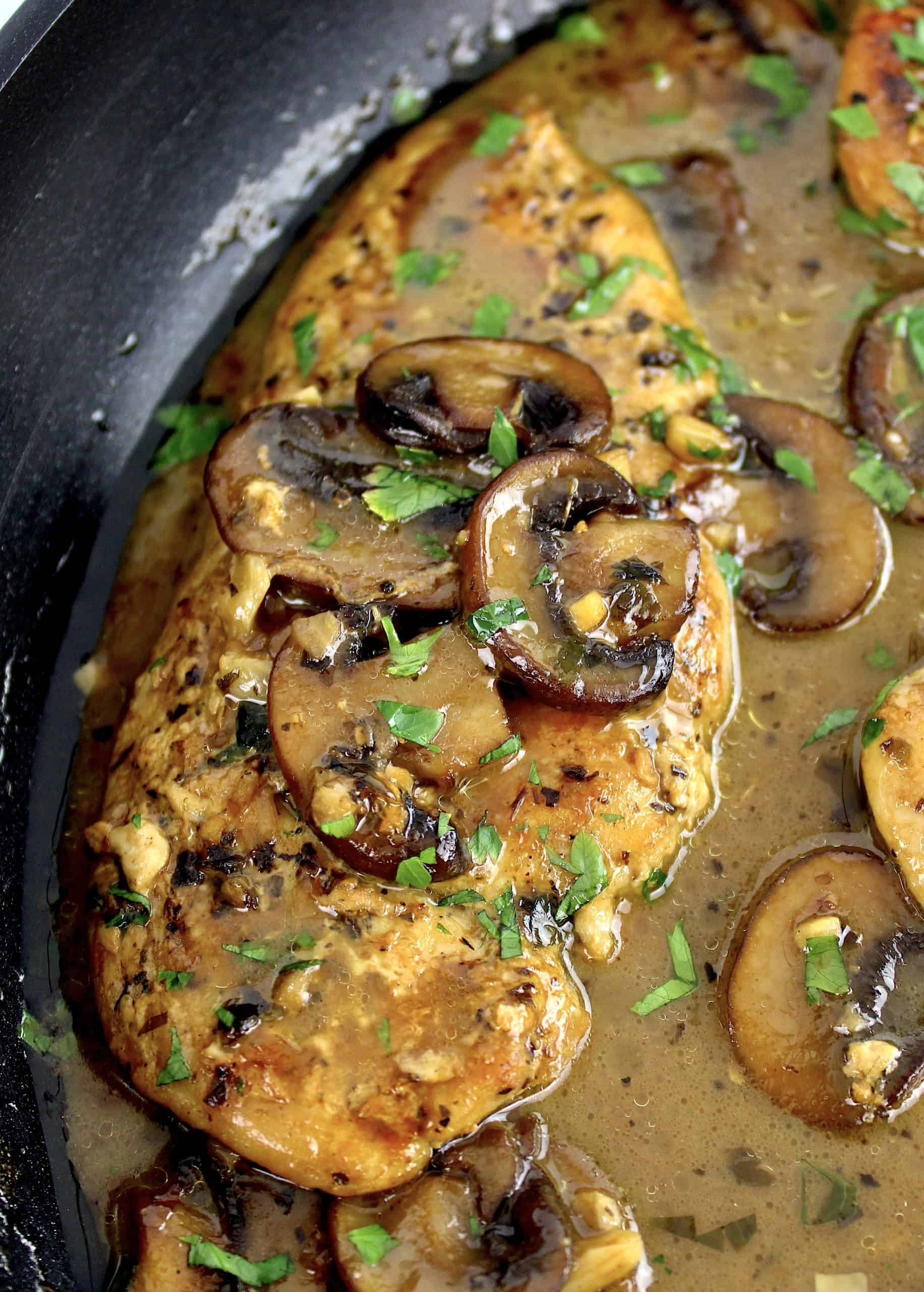 closeup of Creamy Chicken Marsala in skillet with sliced mushrooms and chopped parsley on top