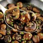 Sautéed Mushrooms in skillet with spoon holding up some