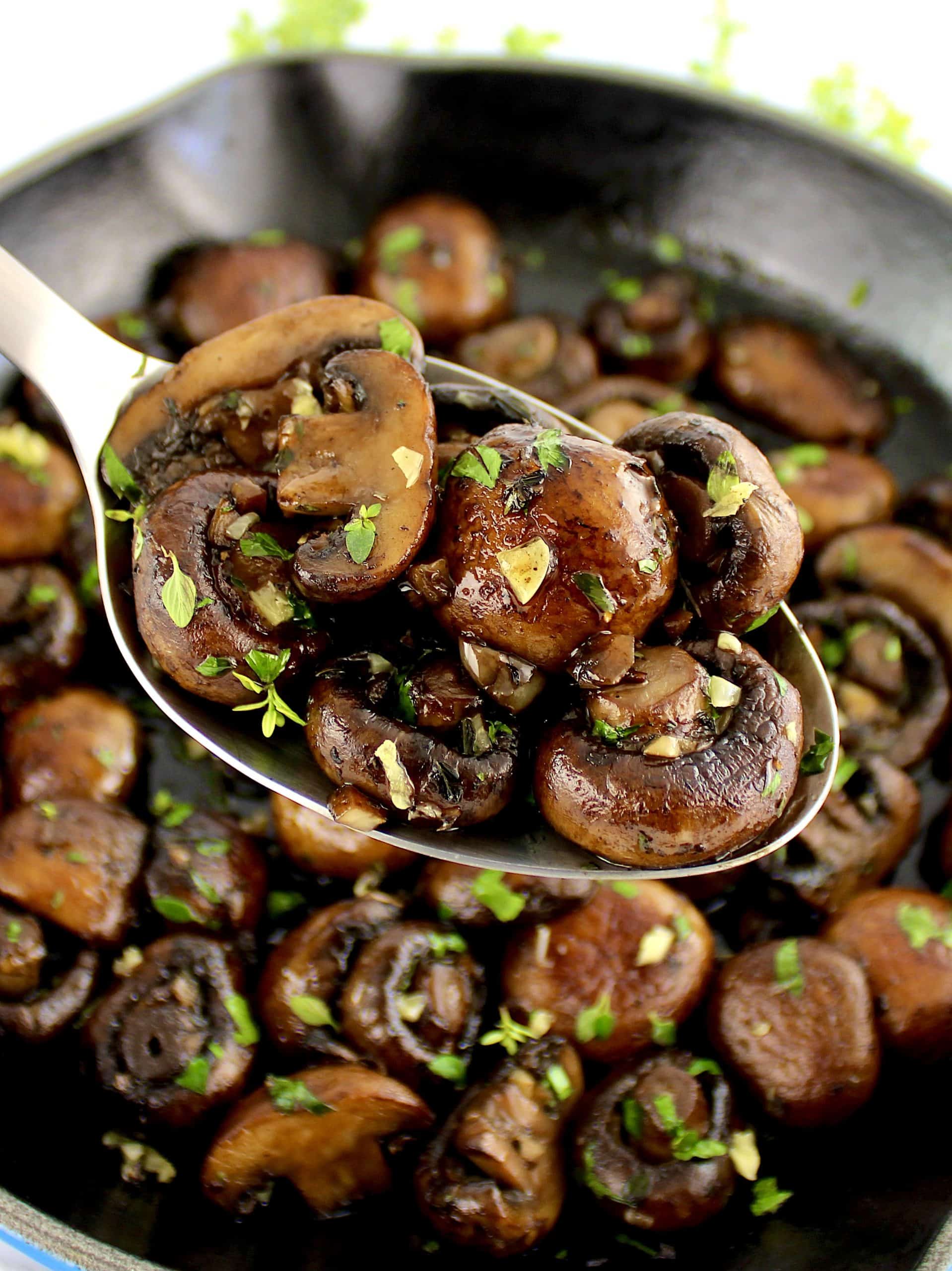 Sautéed Mushrooms in skillet with spoon holding up some