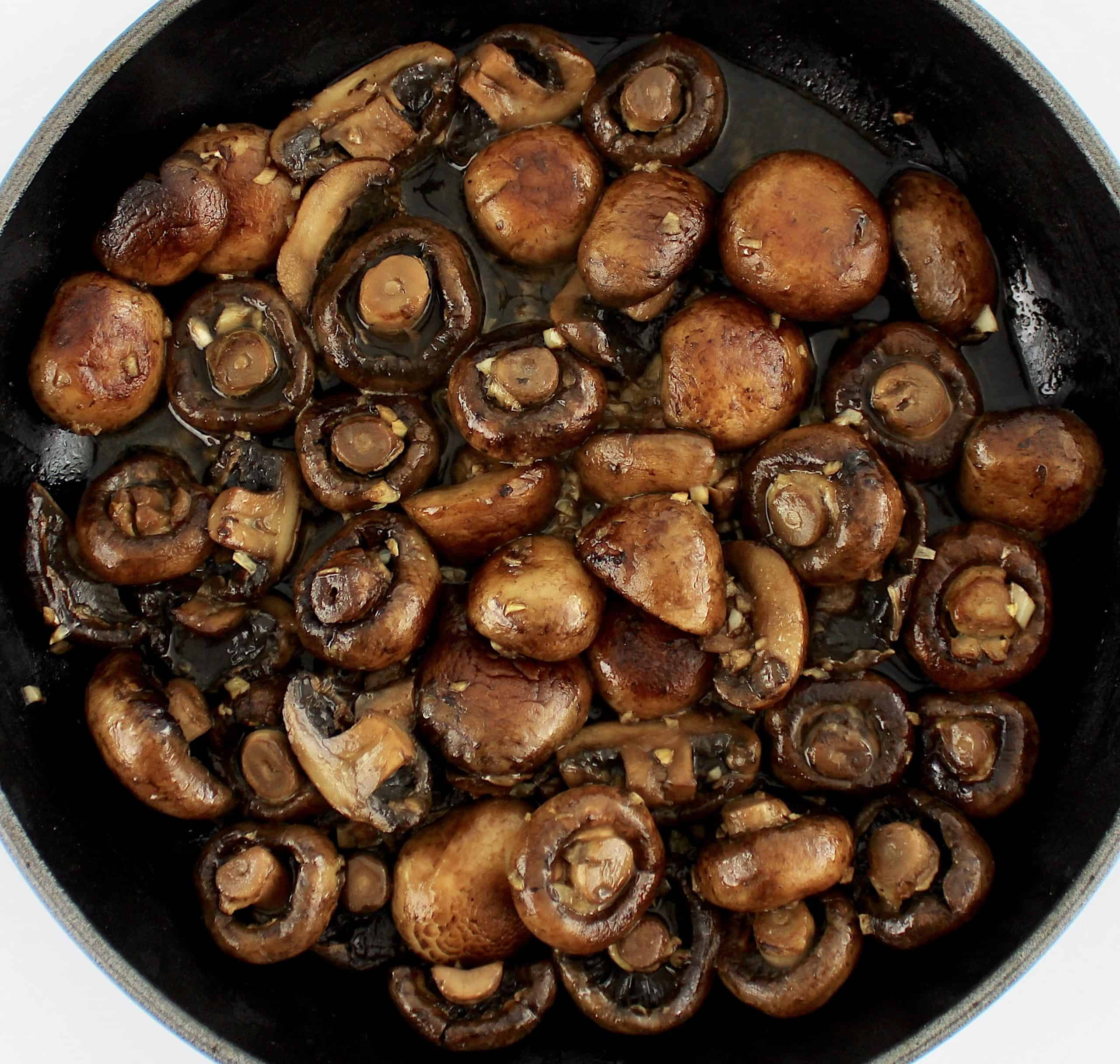 baby bella mushrooms sautéing in skillet with white wine