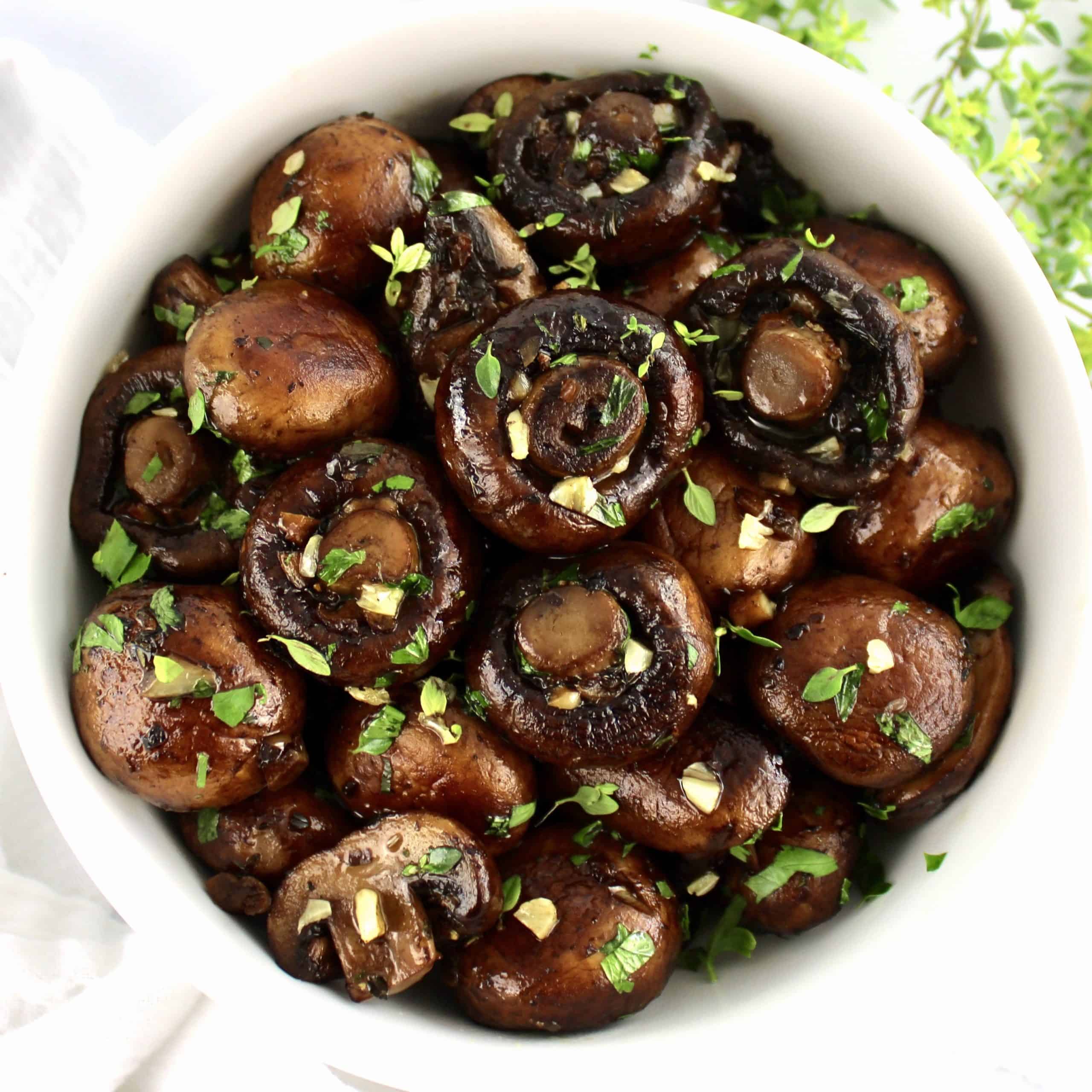 Sautéed Mushrooms in white bowl with chopped parsley on top