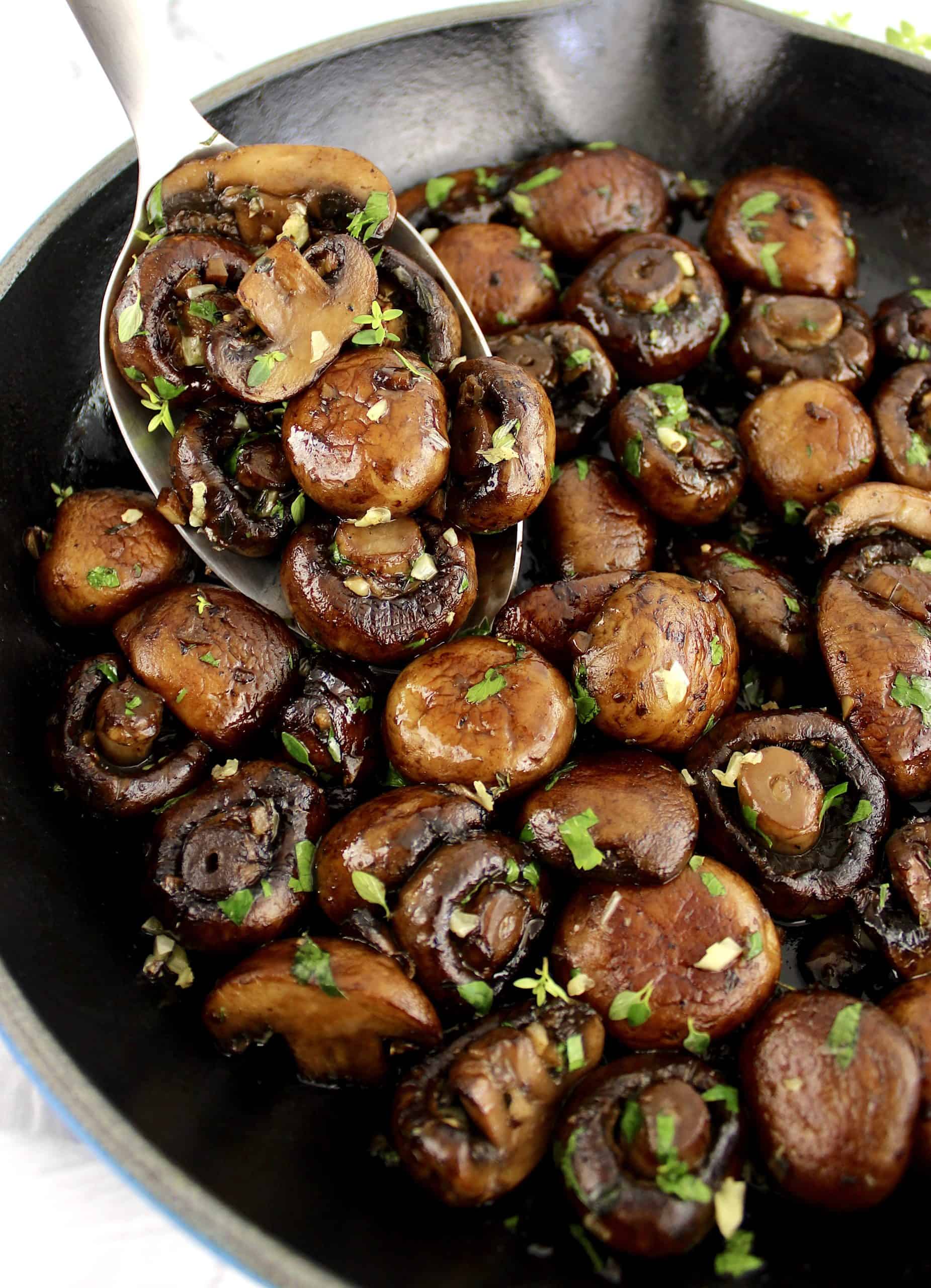 Sautéed Mushrooms in skillet with spoon holding up some