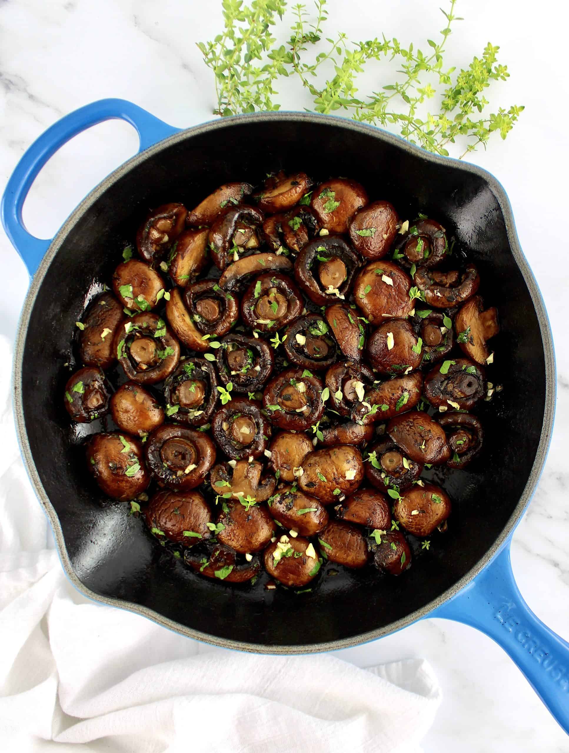 Sautéed Mushrooms in blue skillet with chopped herbs