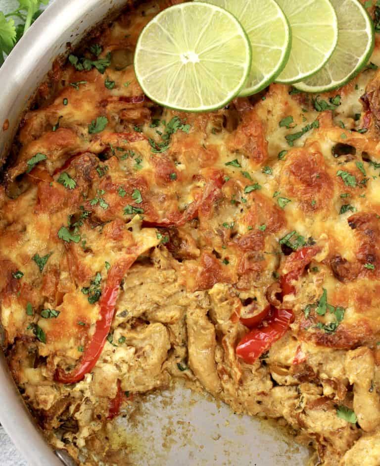 Keto Chicken Fajita Casserole in skillet with some missing and slices of lime on side