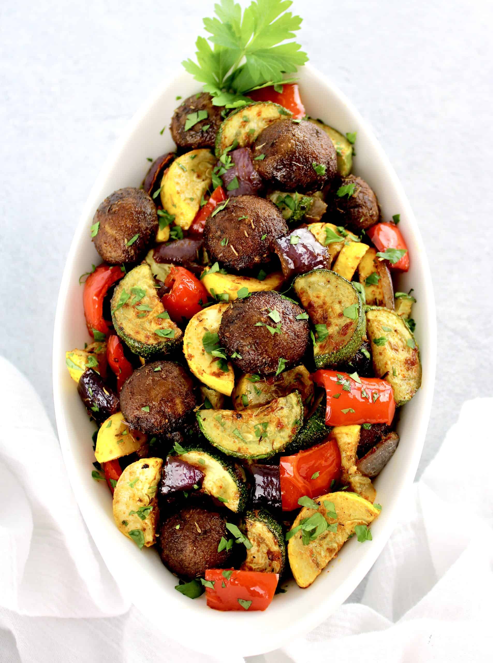 overhead view of Oven Roasted Vegetables in white bowl with parsley garnish