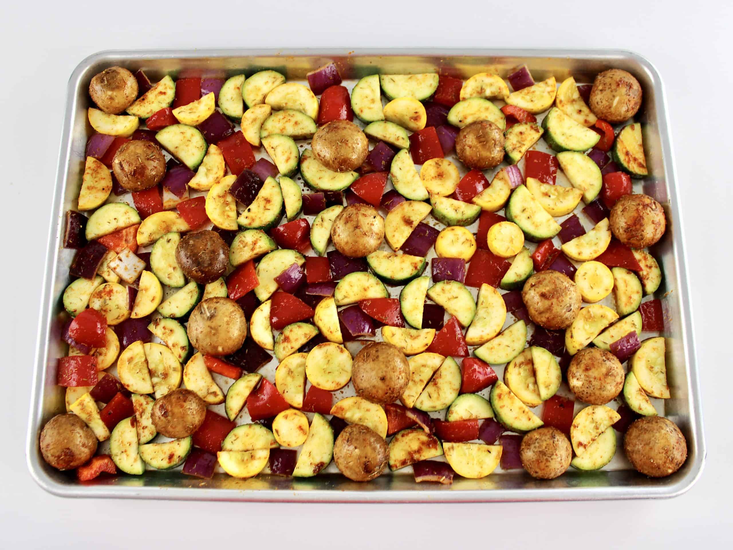 mixed Vegetables with olive oil herbs and spices mixed on sheet pan