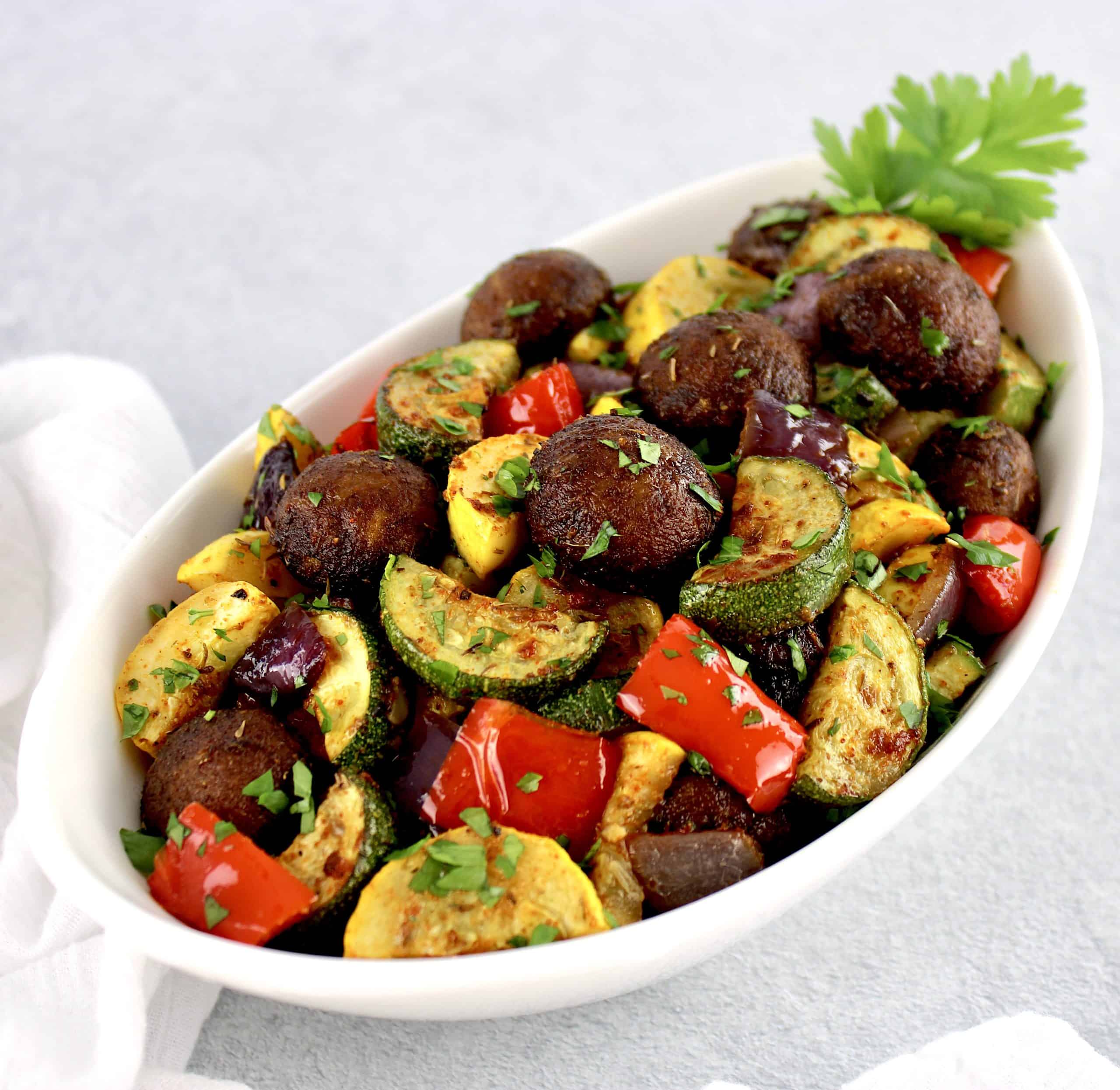 Oven Roasted Vegetables in white bowl with parsley garnish