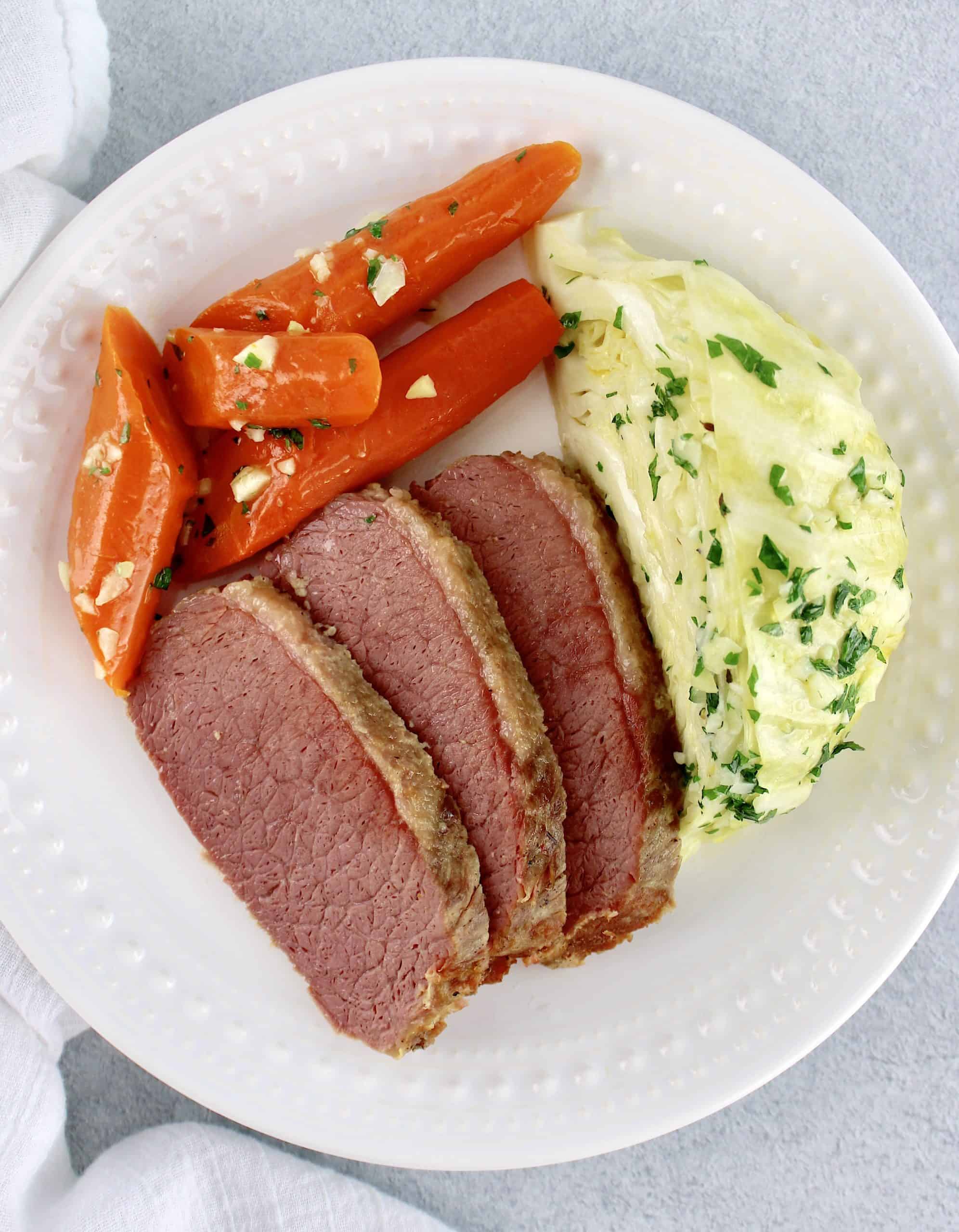 3 slices of corned beef carrots and cabbage wedge on white plate