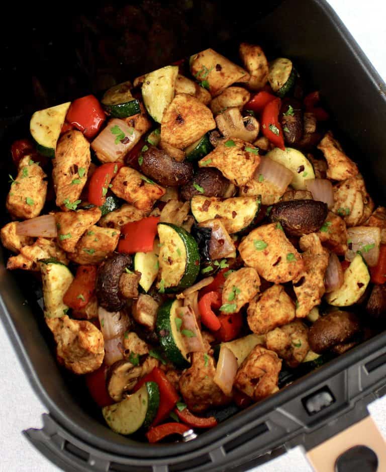 Air Fryer Chicken Bites with Veggies in air fryer basket with chopped parsley