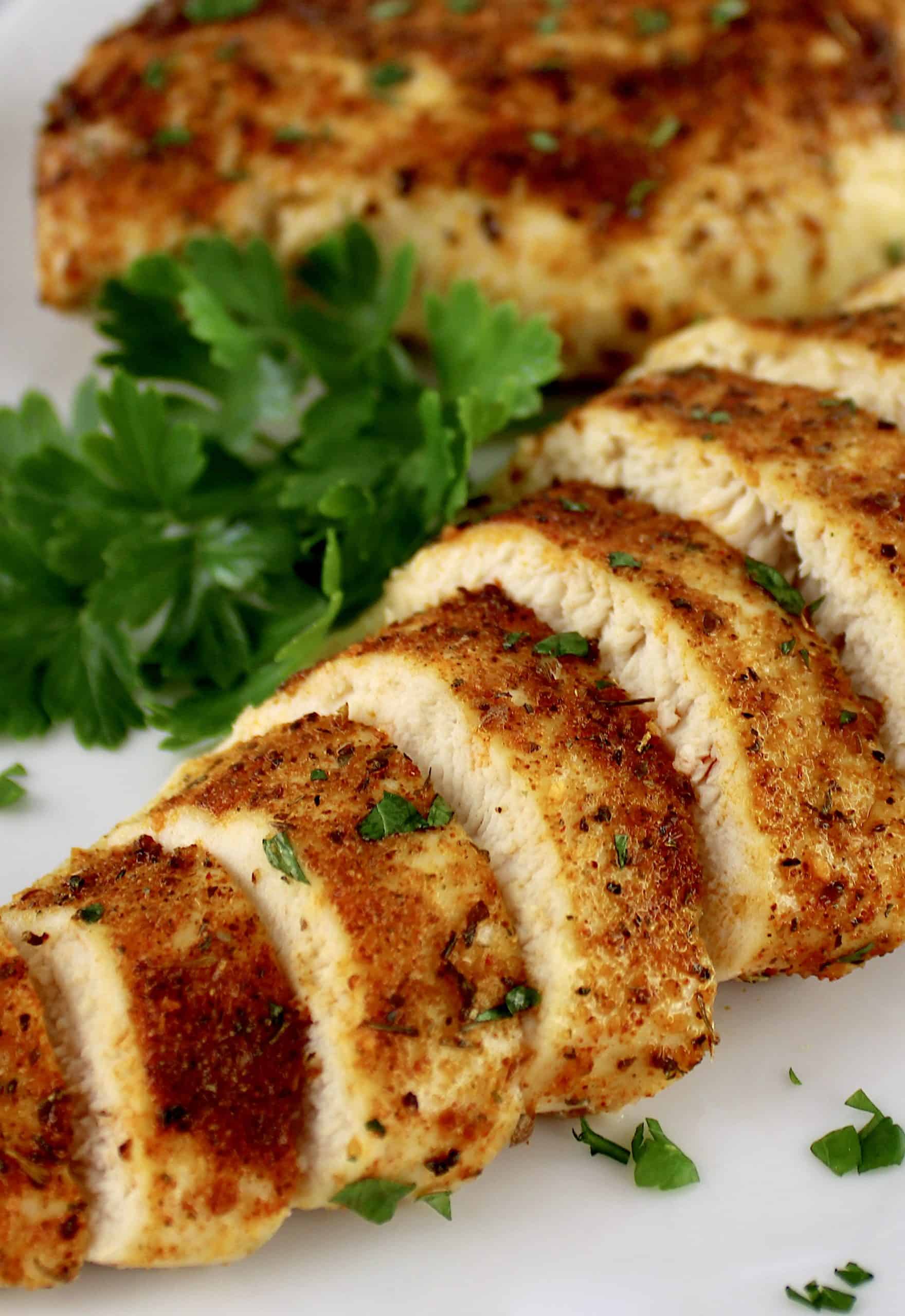 Air Fryer Italian Chicken breast sliced on white plate with parsley garnish