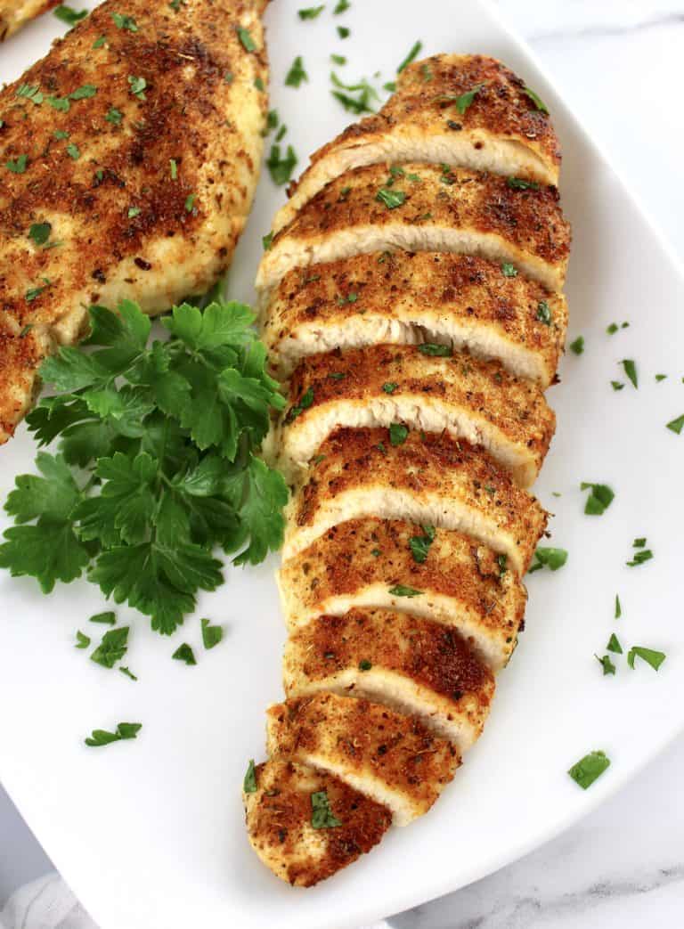 Air Fryer Italian Chicken breast sliced on white plate with parsley garnish