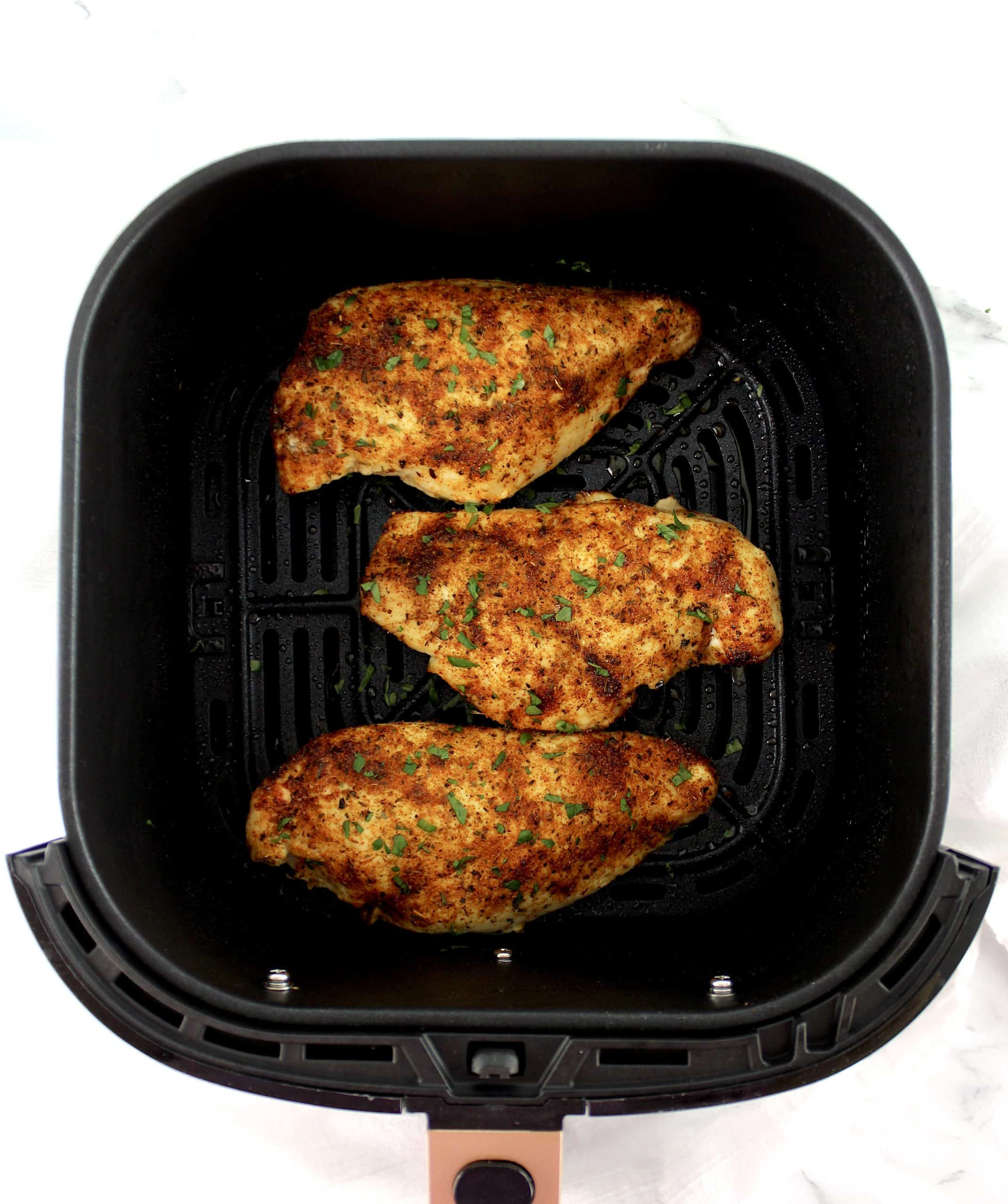 3 cooked Italian seasoned Chicken breasts in air fryer basket