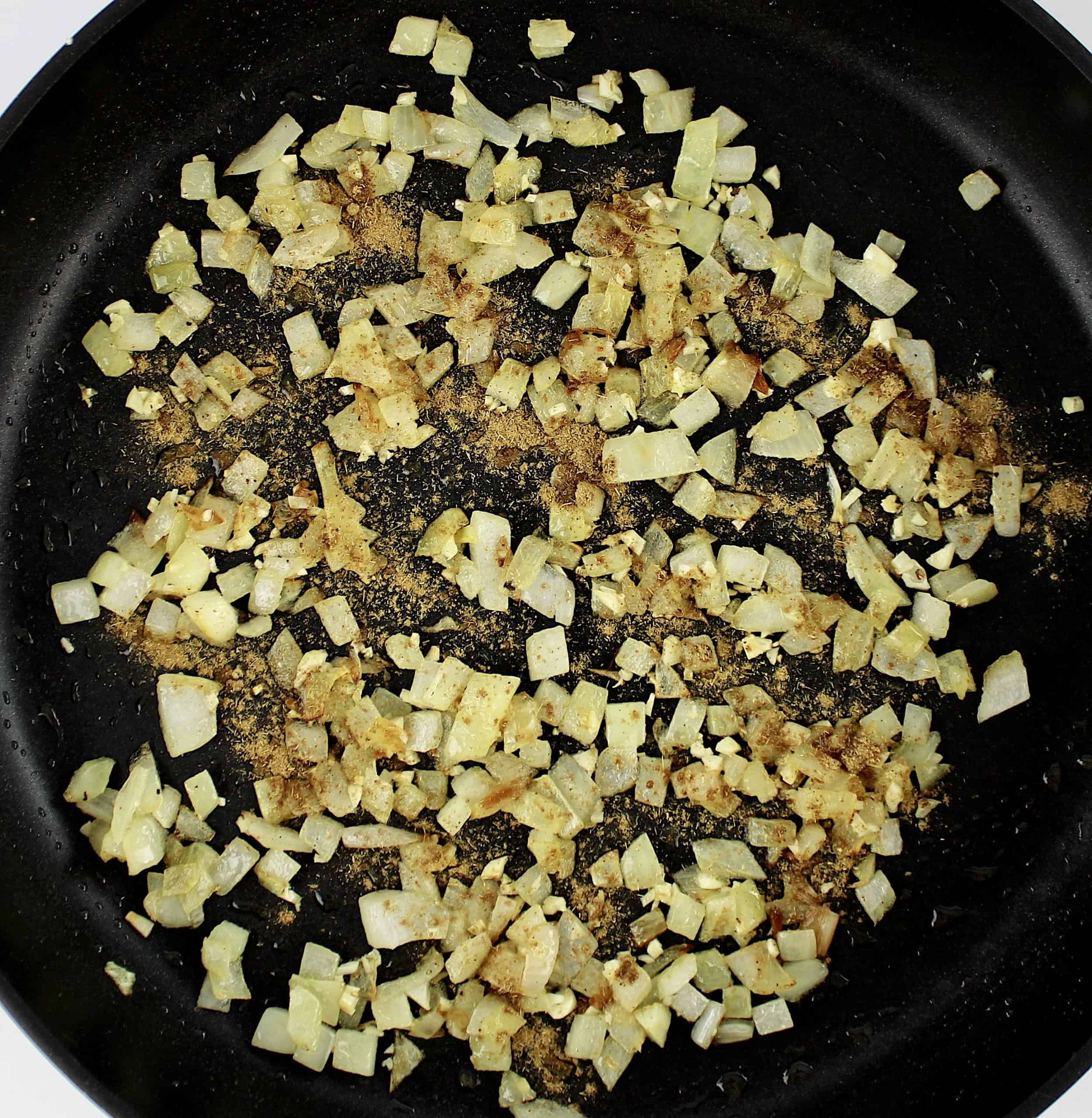 minced onion and garlic in skillet with ground cumin