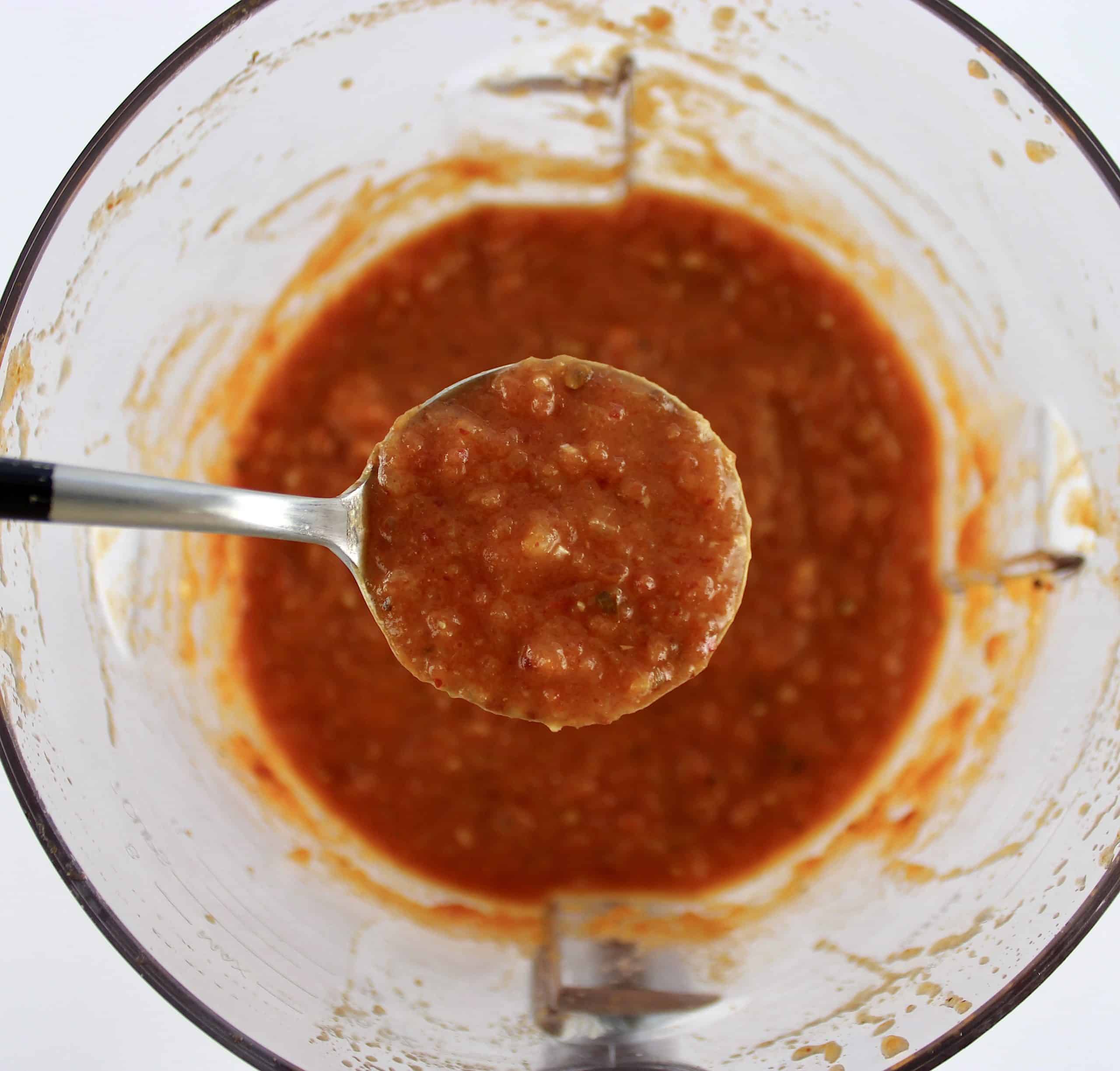 Chicken Tinga sauce in food processor bowl with spoon holding up some