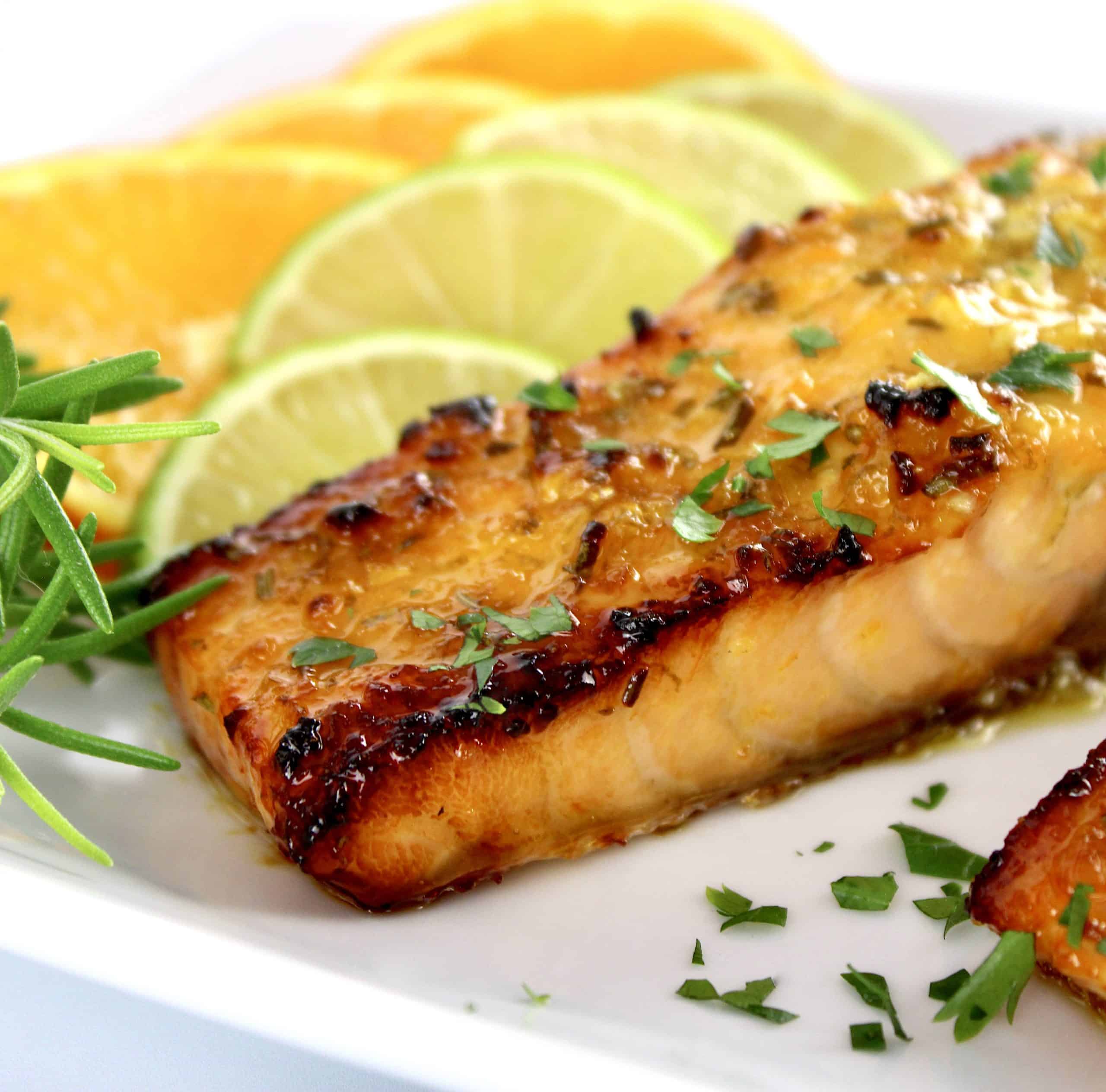 closeup of Citrus Glazed Salmon with orange and lime slices on white plate