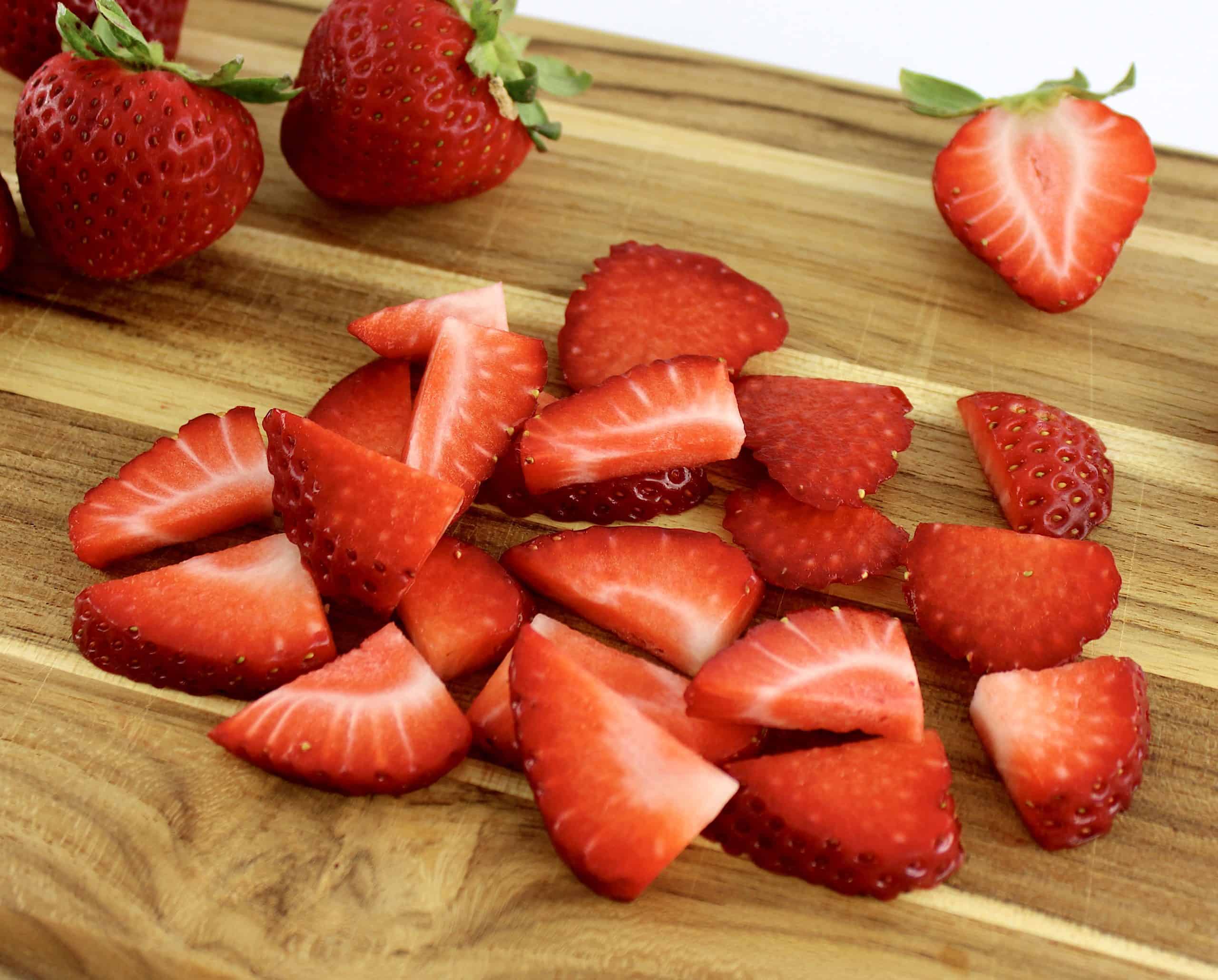 sliced and whole strawberries on cutting board