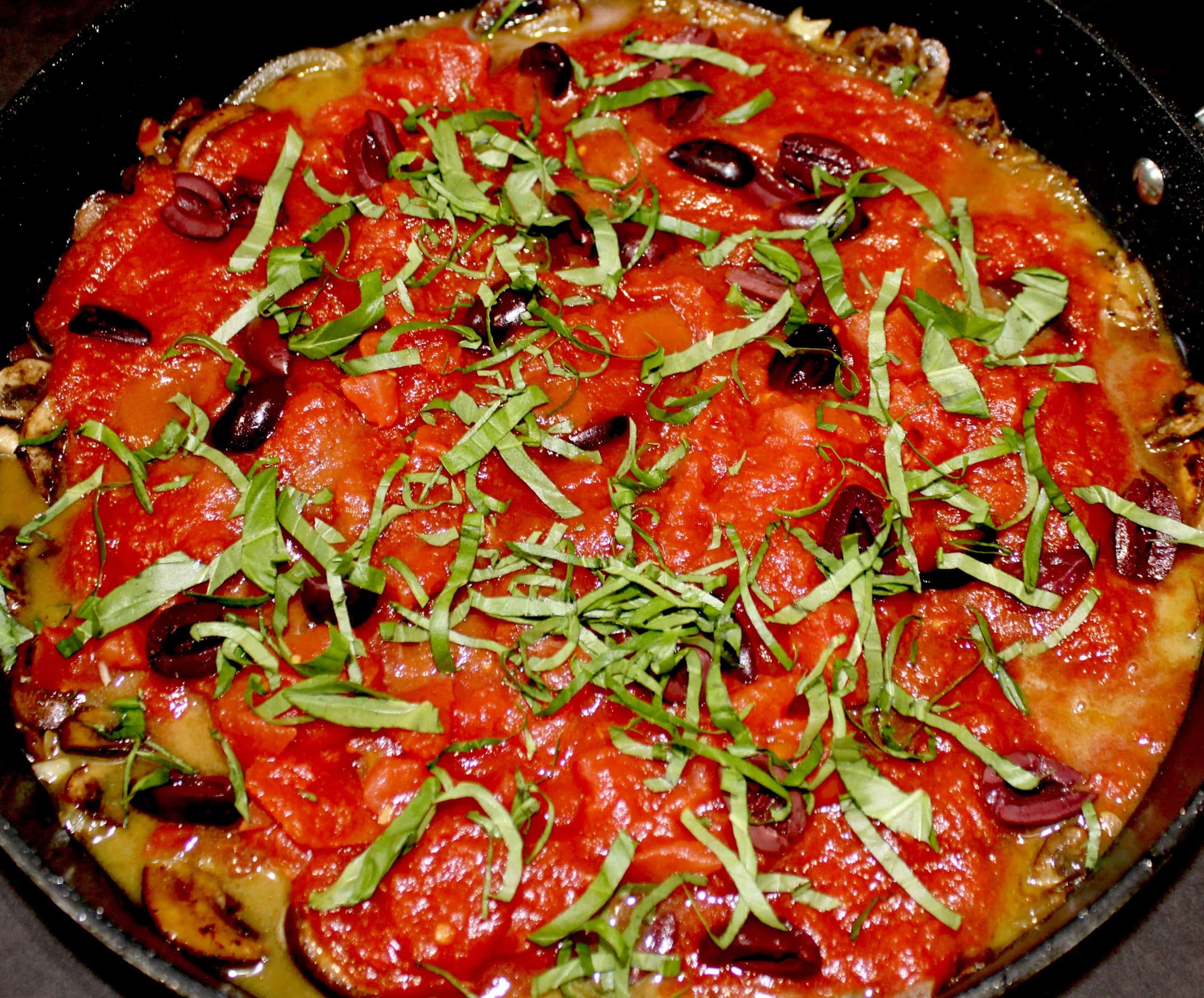 Keto Chicken Cacciatore cooking in skillet with sliced basil on top