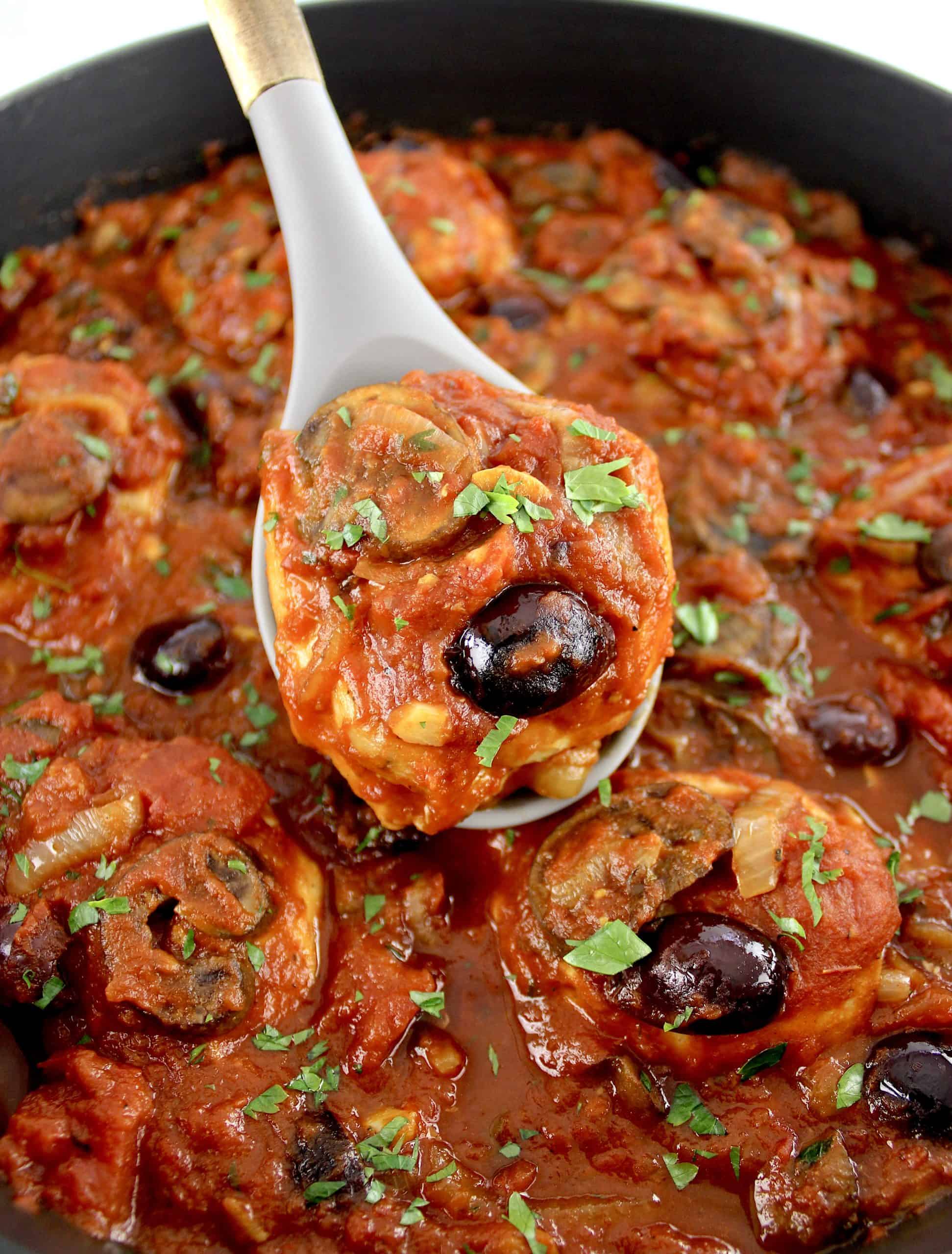 Keto Chicken Cacciatore in pan being held up with spoon
