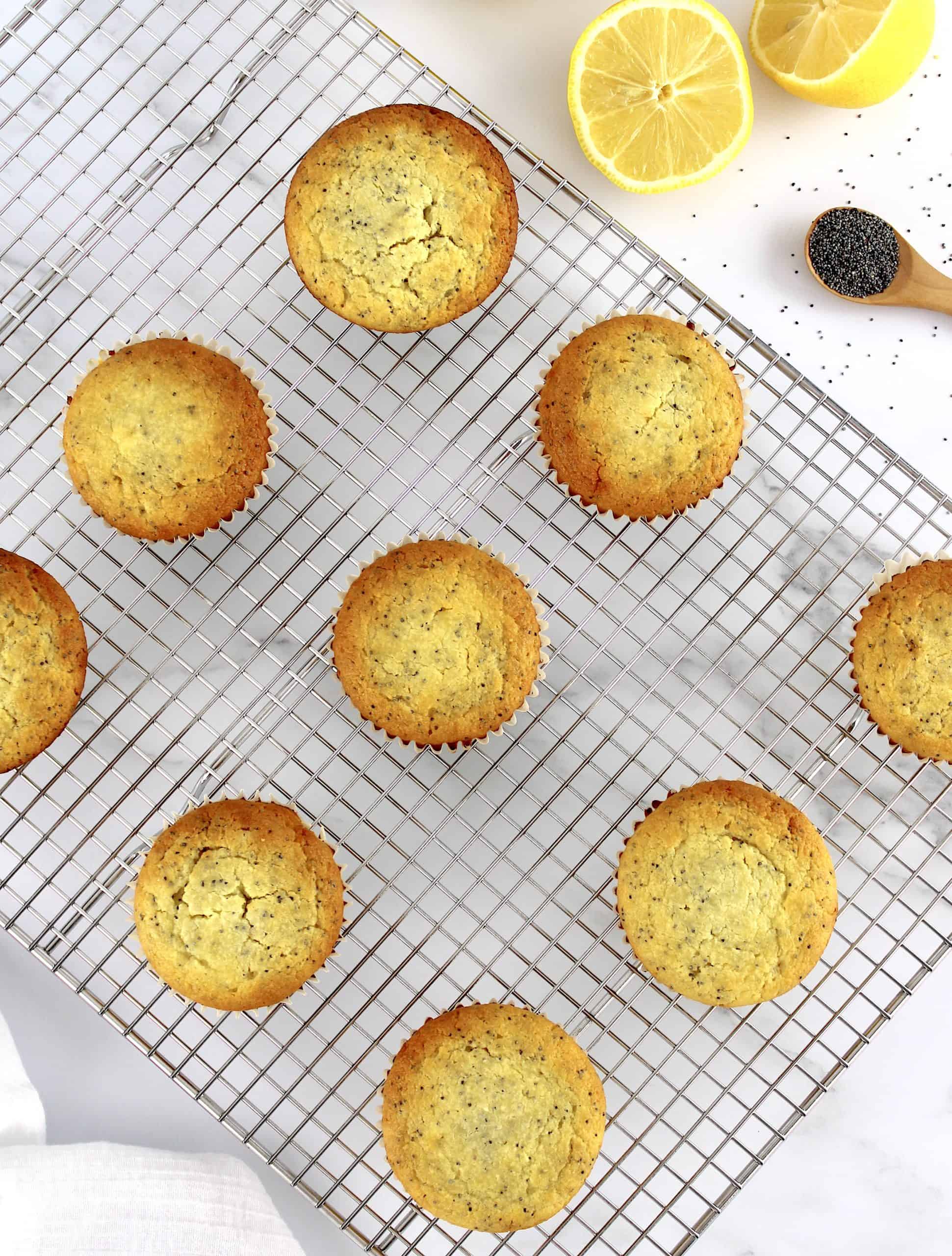 overhead view of Keto Lemon Poppy Seed Muffins on cooling rack with lemons in back