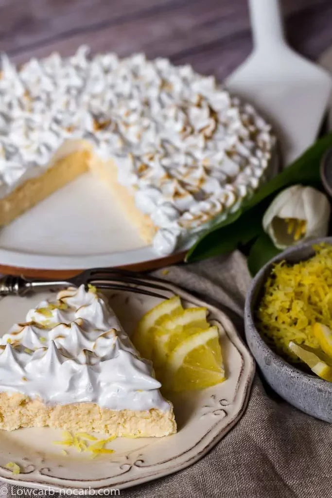 slice of lemon cheesecake on plate with rest of cheesecake in background