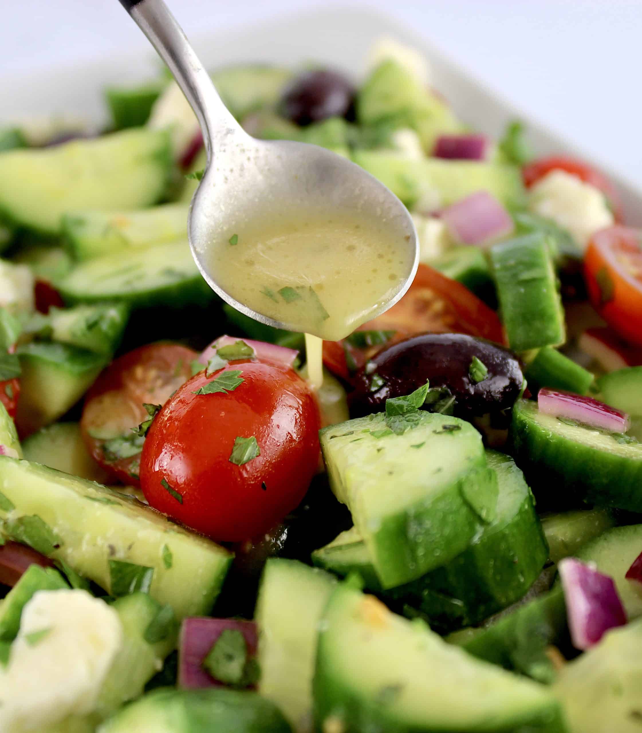 closeup of dressing being spooned over Mediterranean Cucumber Salad