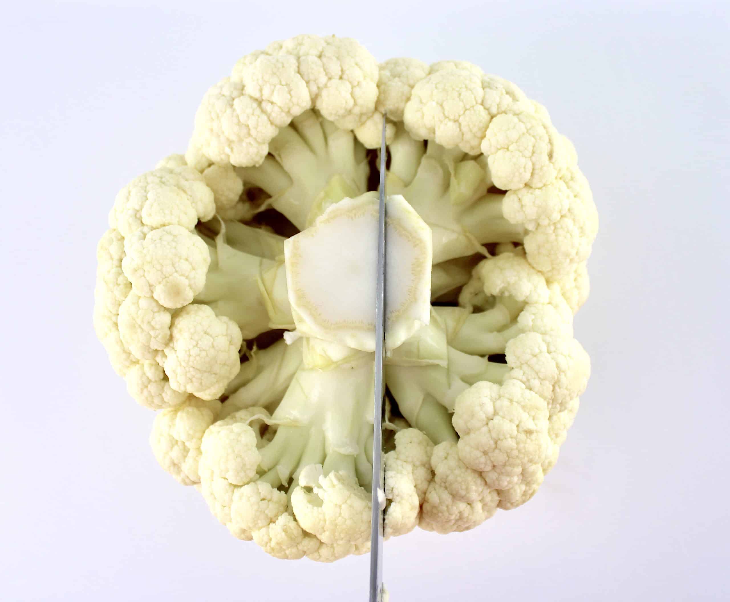 head of cauliflower being cut from the stem down