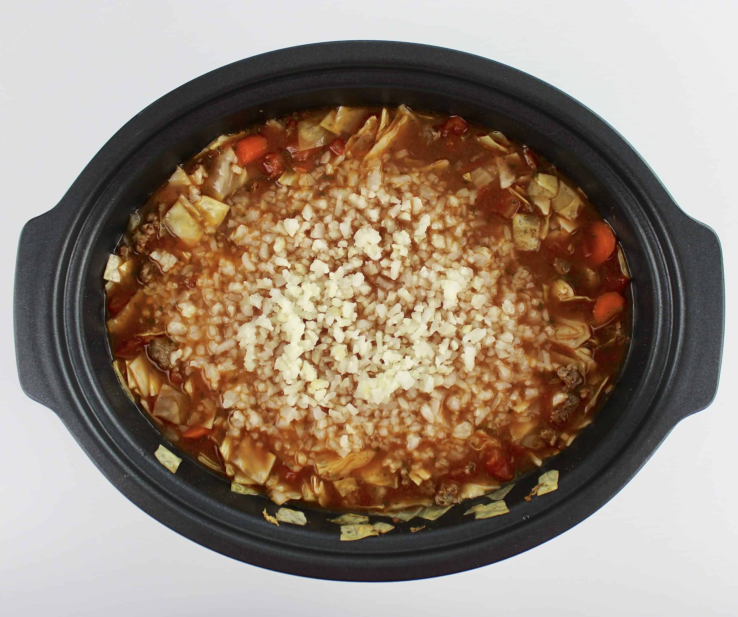 Slow Cooker Cabbage Roll Soup in slow cooker with raw cauliflower rice on top