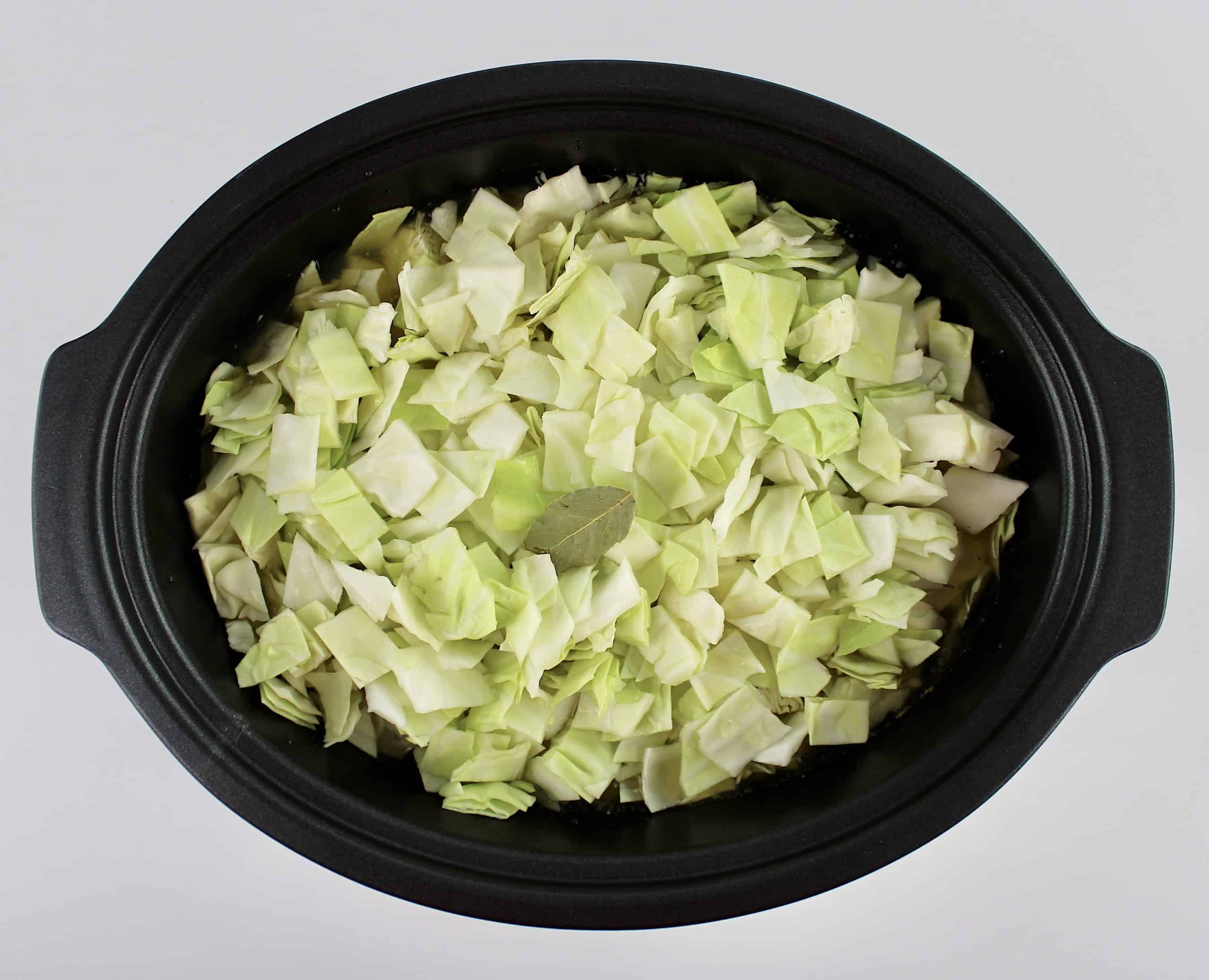 chopped raw cabbage and bay leaf in slow cooker
