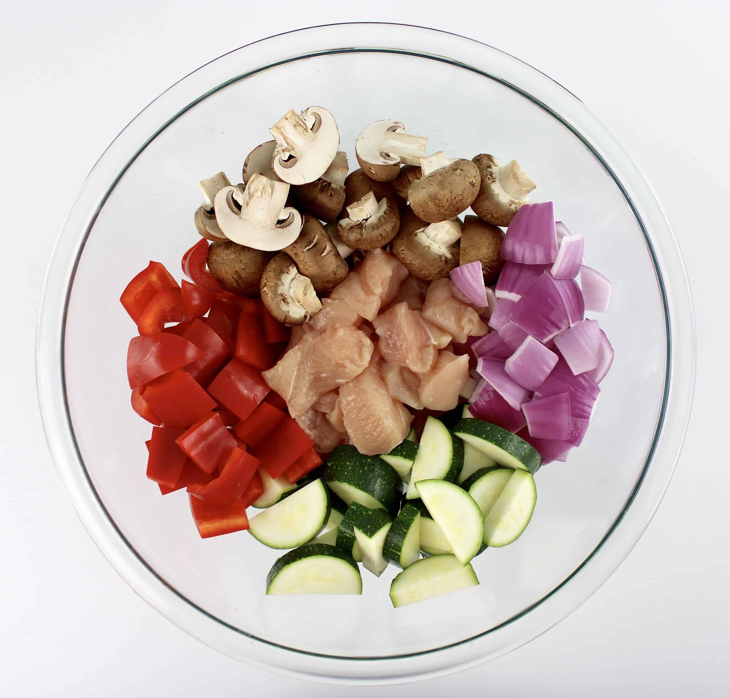 chopped chicken zucchini red onion mushrooms and red pepper in glass bowl