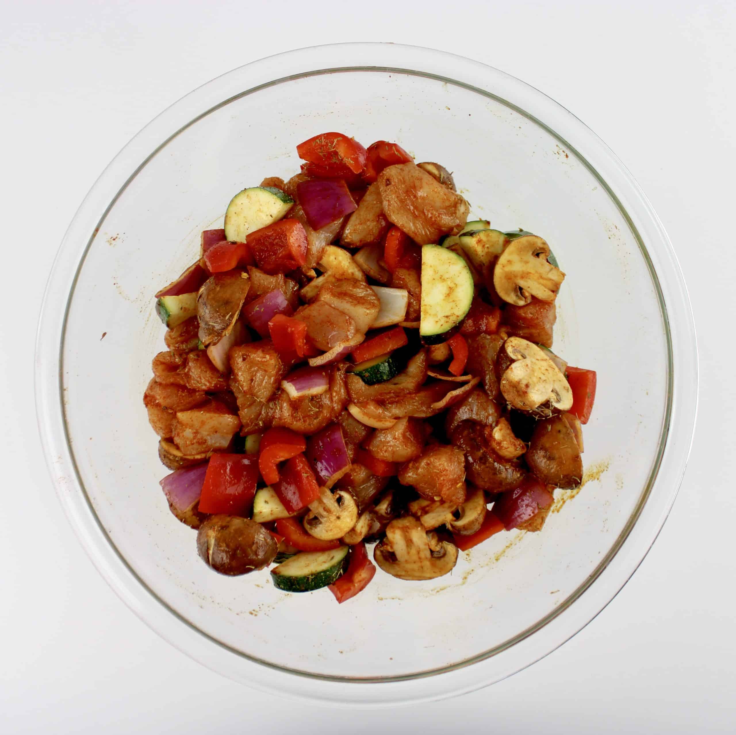 chopped chicken zucchini red onion mushrooms and red pepper in glass bowl with spices and herbs