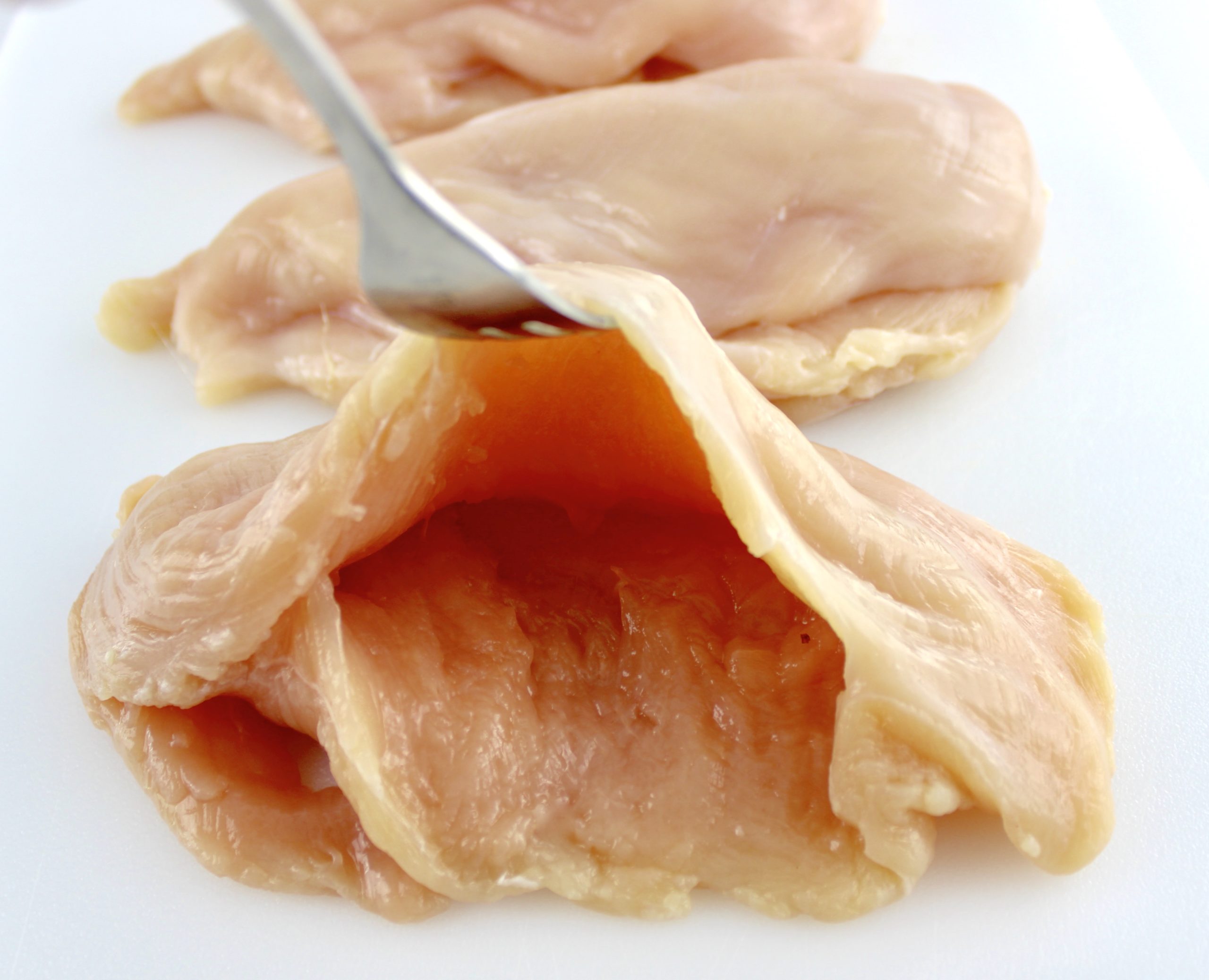 chicken breast cut open being held open with fork