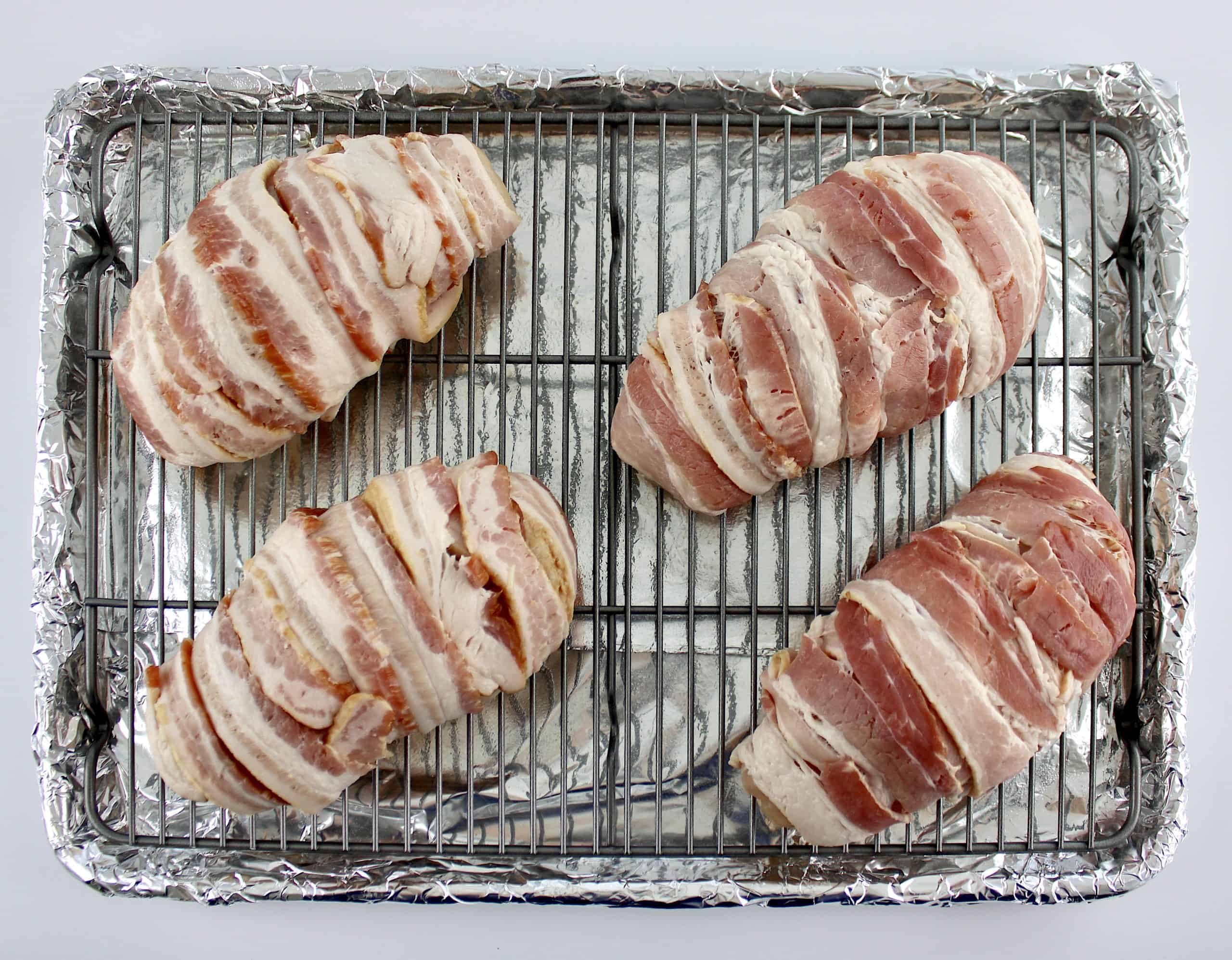 4 bacon wrapped chicken breasts on baking rack lined sheet pan