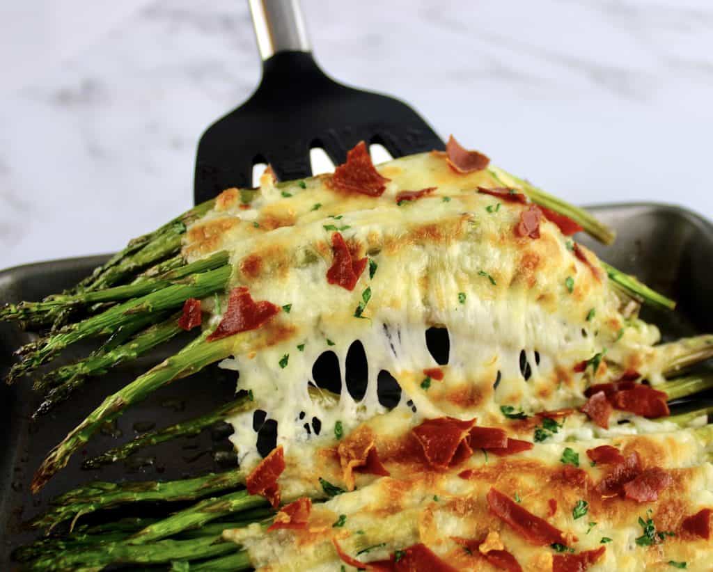 Cheesy Roasted Asparagus being held up with spatula