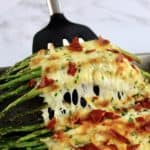 Cheesy Roasted Asparagus being held up with spatula
