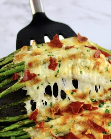 Cheesy Roasted Asparagus being held up with spatula