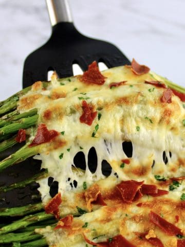 Cheesy Roasted Asparagus being held up with spatula