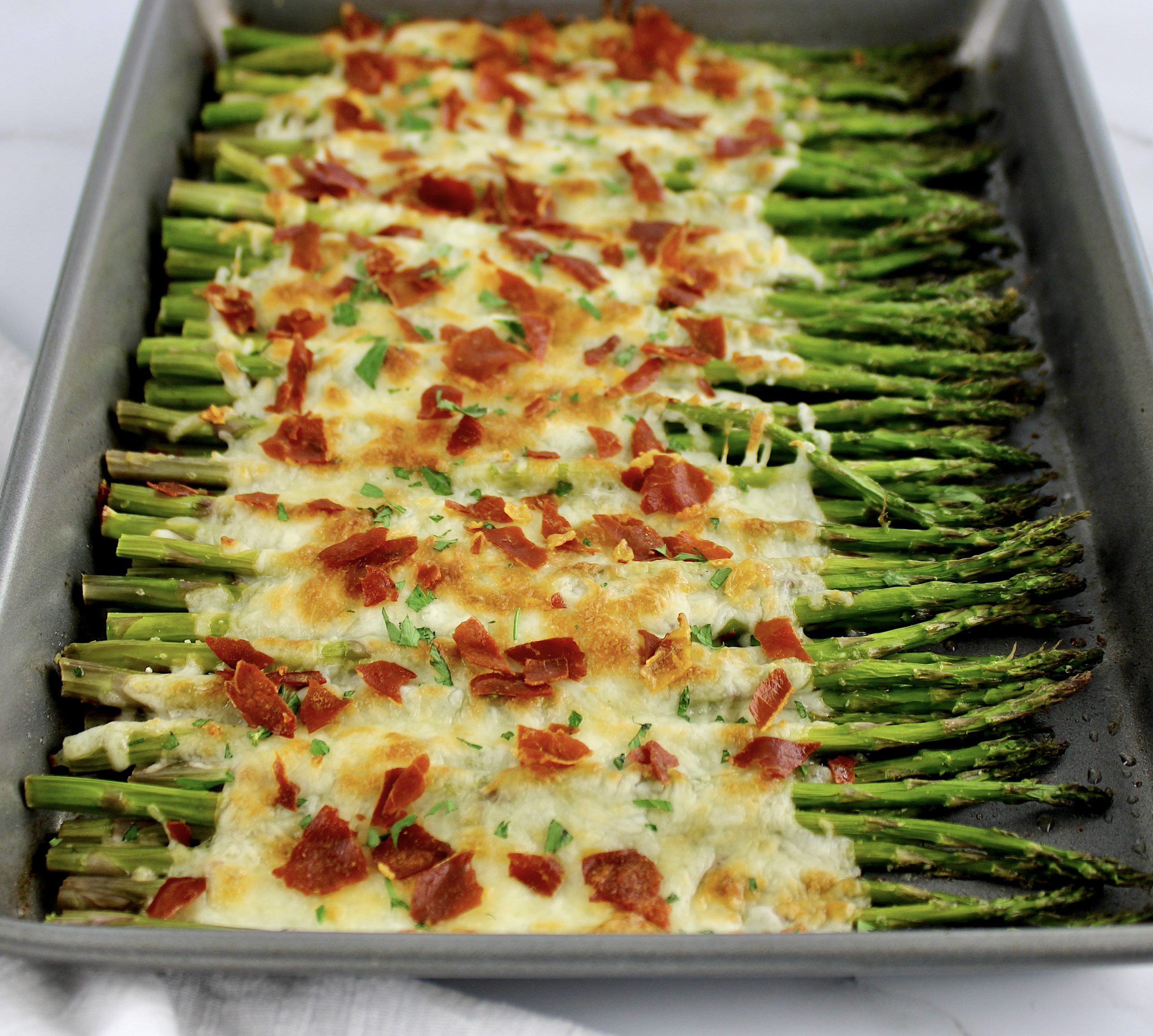 Cheesy Roasted Asparagus on baking sheet with crispy prosciutto on top
