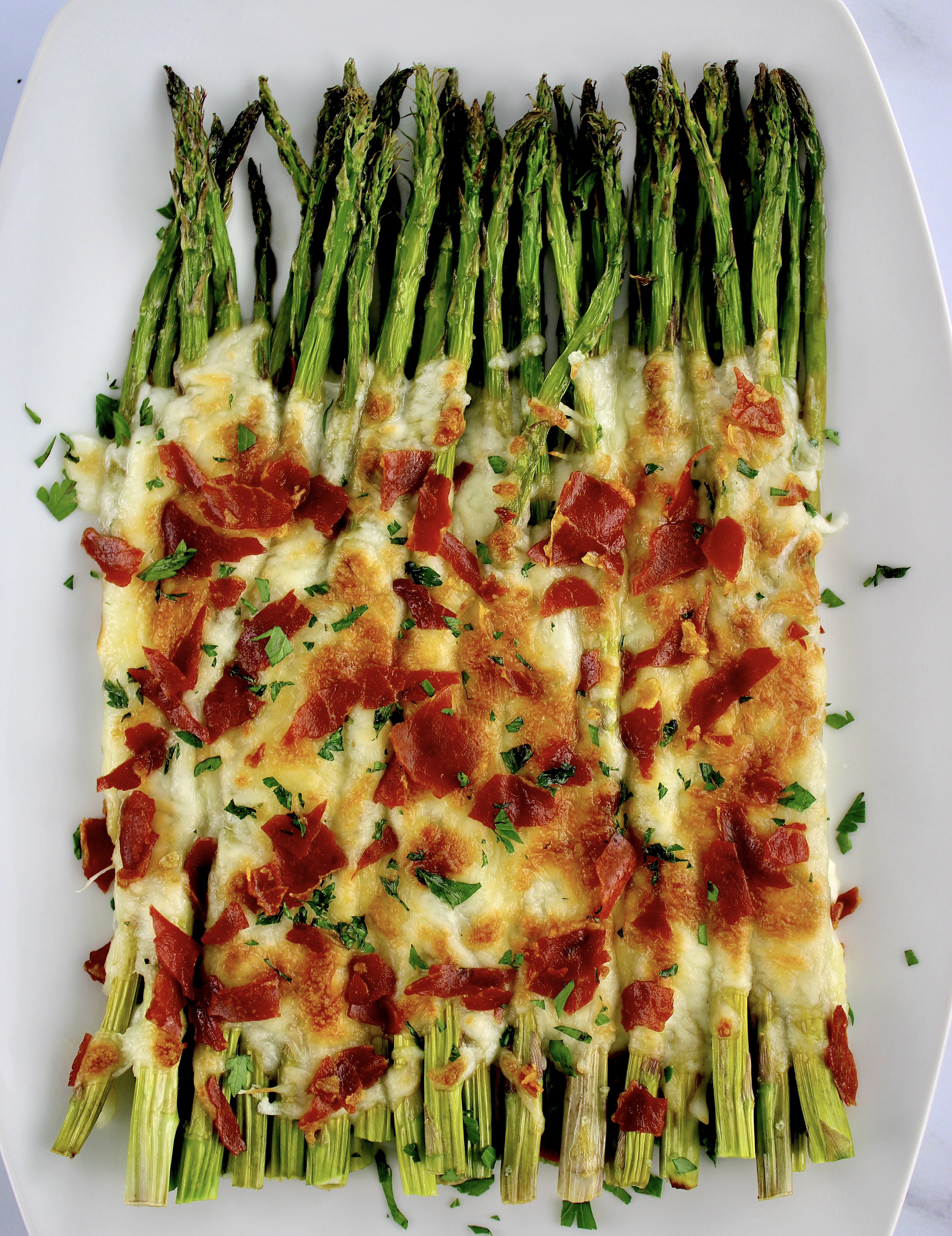 overhead view of Cheesy Roasted Asparagus with crumbled prosciutto on top
