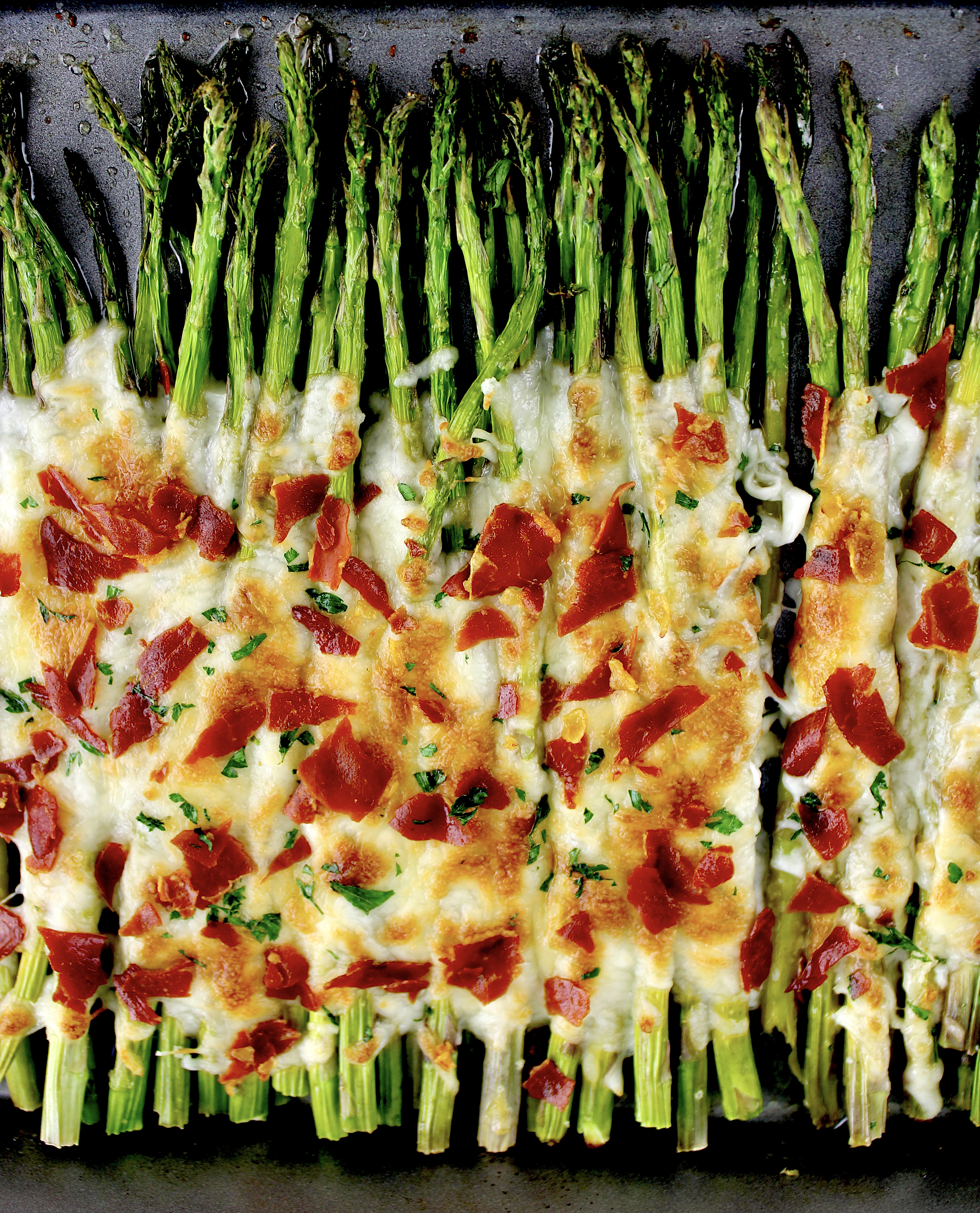 Cheesy Roasted Asparagus on baking sheet with crispy prosciutto on top