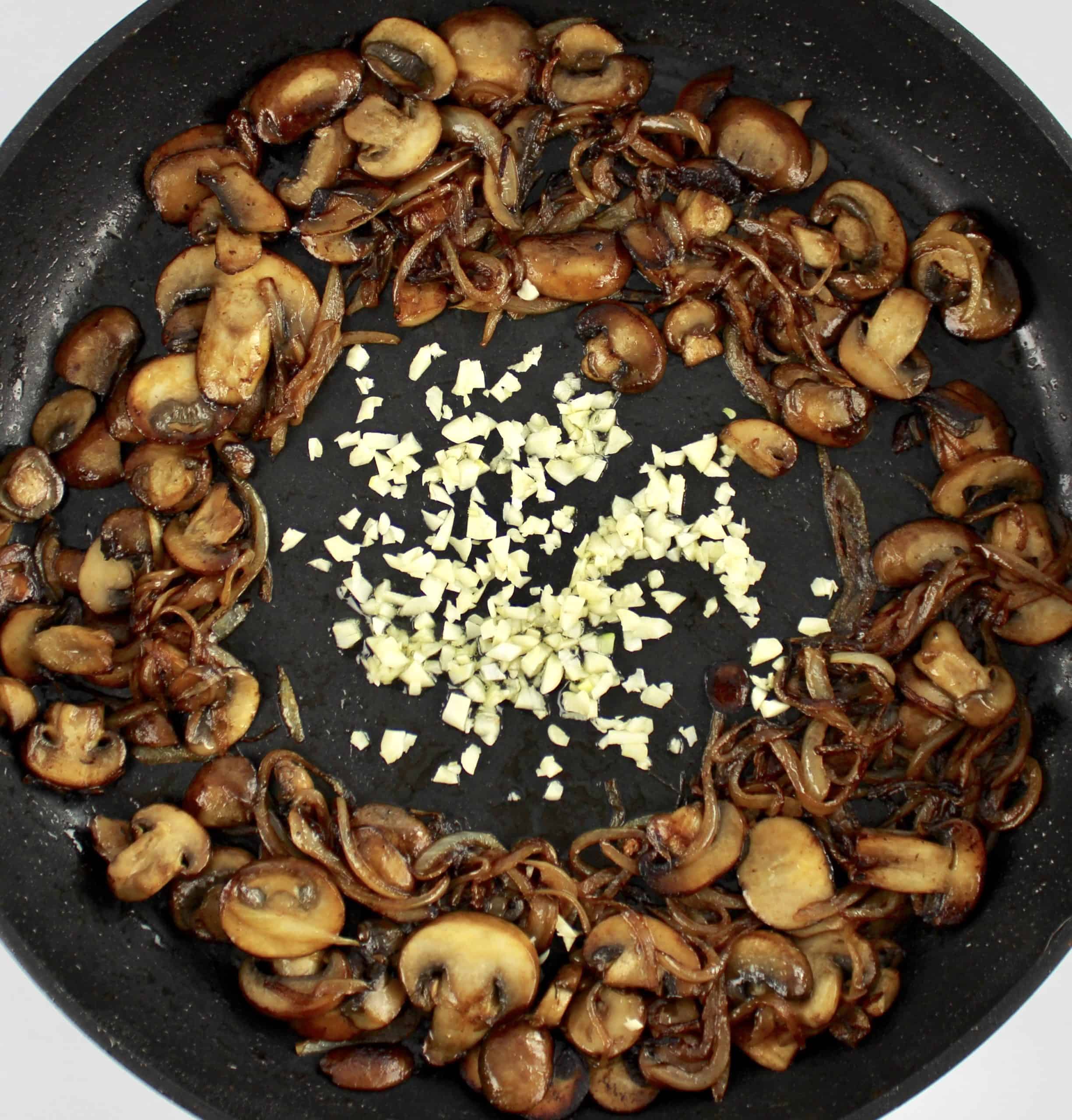 cooked sliced mushrooms and onions in skillet with minced garlic in the center
