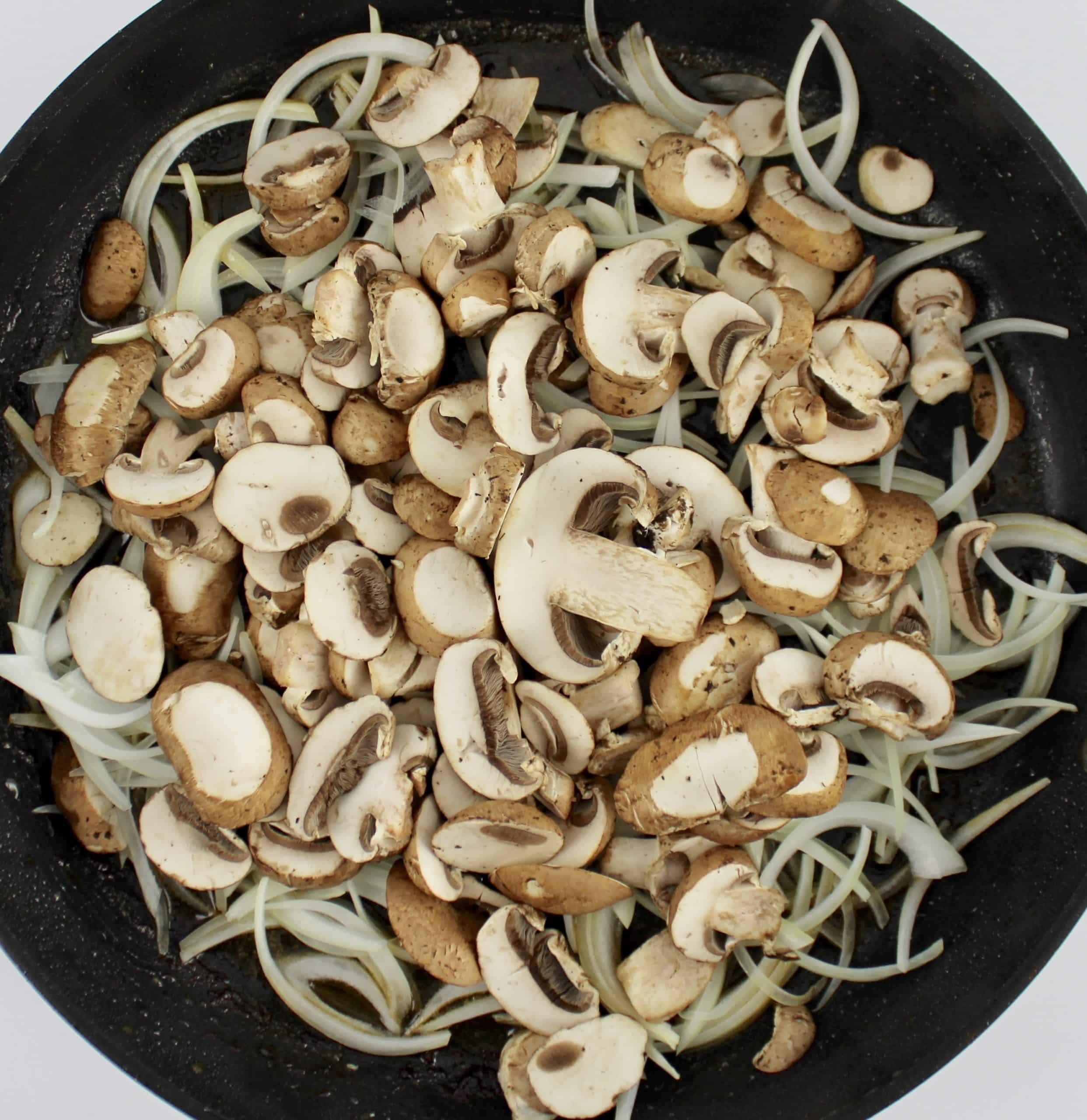 sliced raw mushrooms and onions in skillet