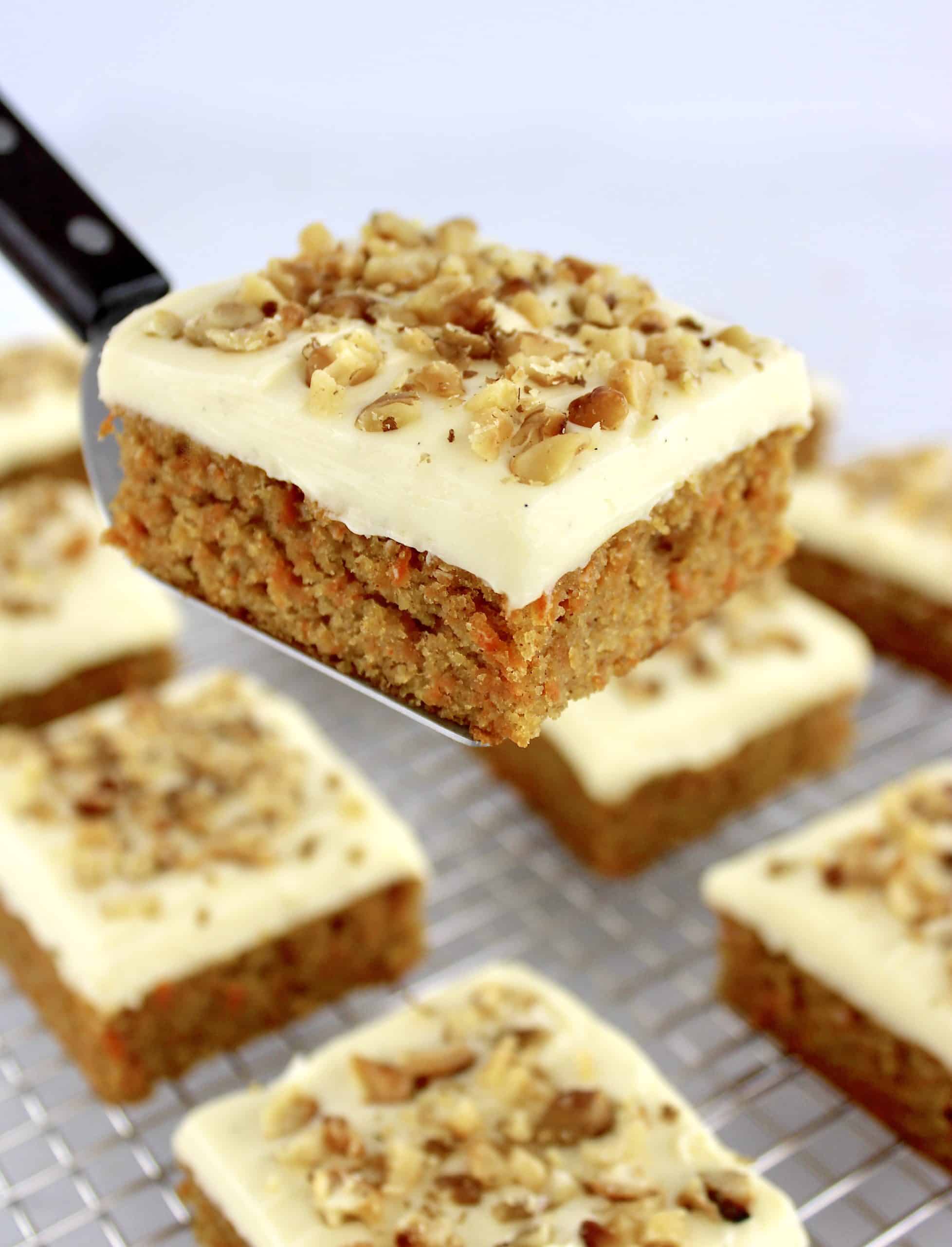 Keto Carrot Cake Bar held up by spatula with more bars in background on cooling rack