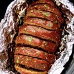 Keto Crockpot Meatloaf with tomato glaze on top sliced in foil lined crockpot
