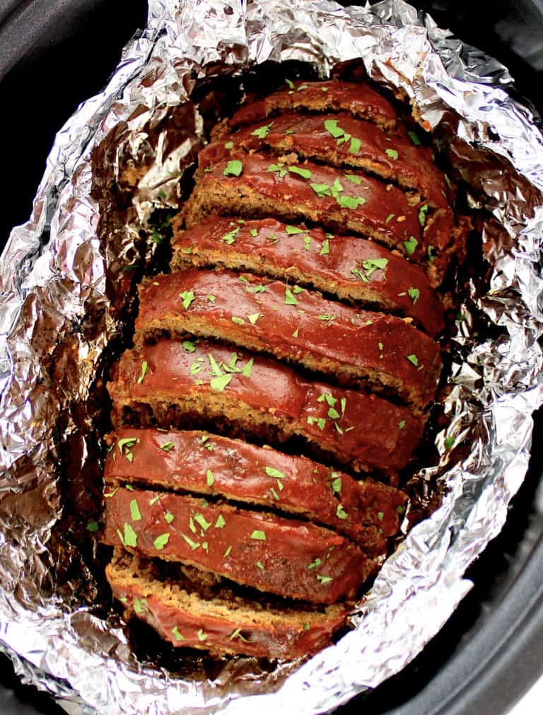Keto Crockpot Meatloaf with tomato glaze on top sliced in foil lined crockpot