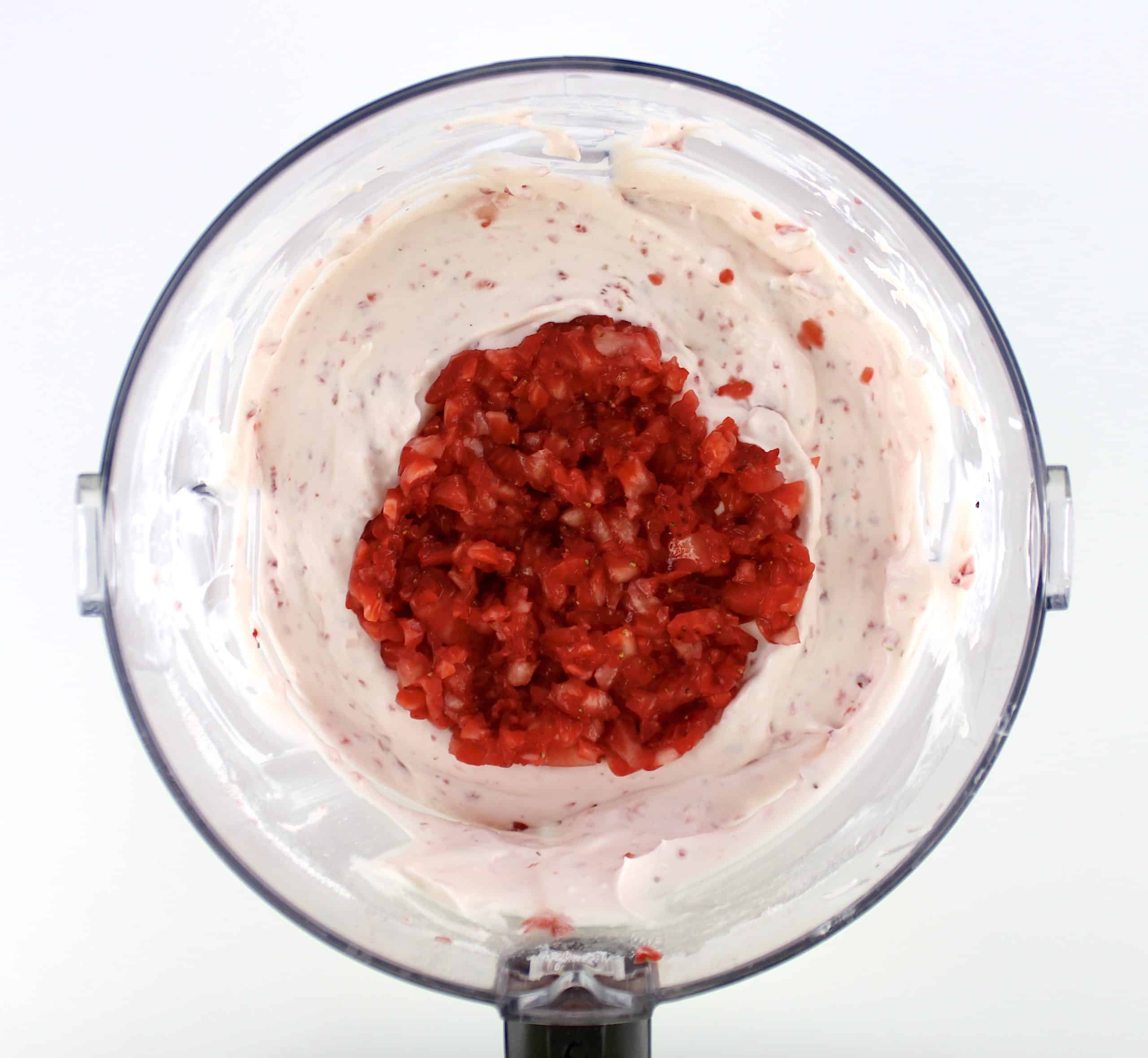Keto Strawberry Cheesecake Popsicle ingredients in food processor with chopped strawberries on top