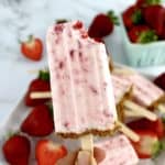 Keto Strawberry Cheesecake Popsicle being held up with bite missing