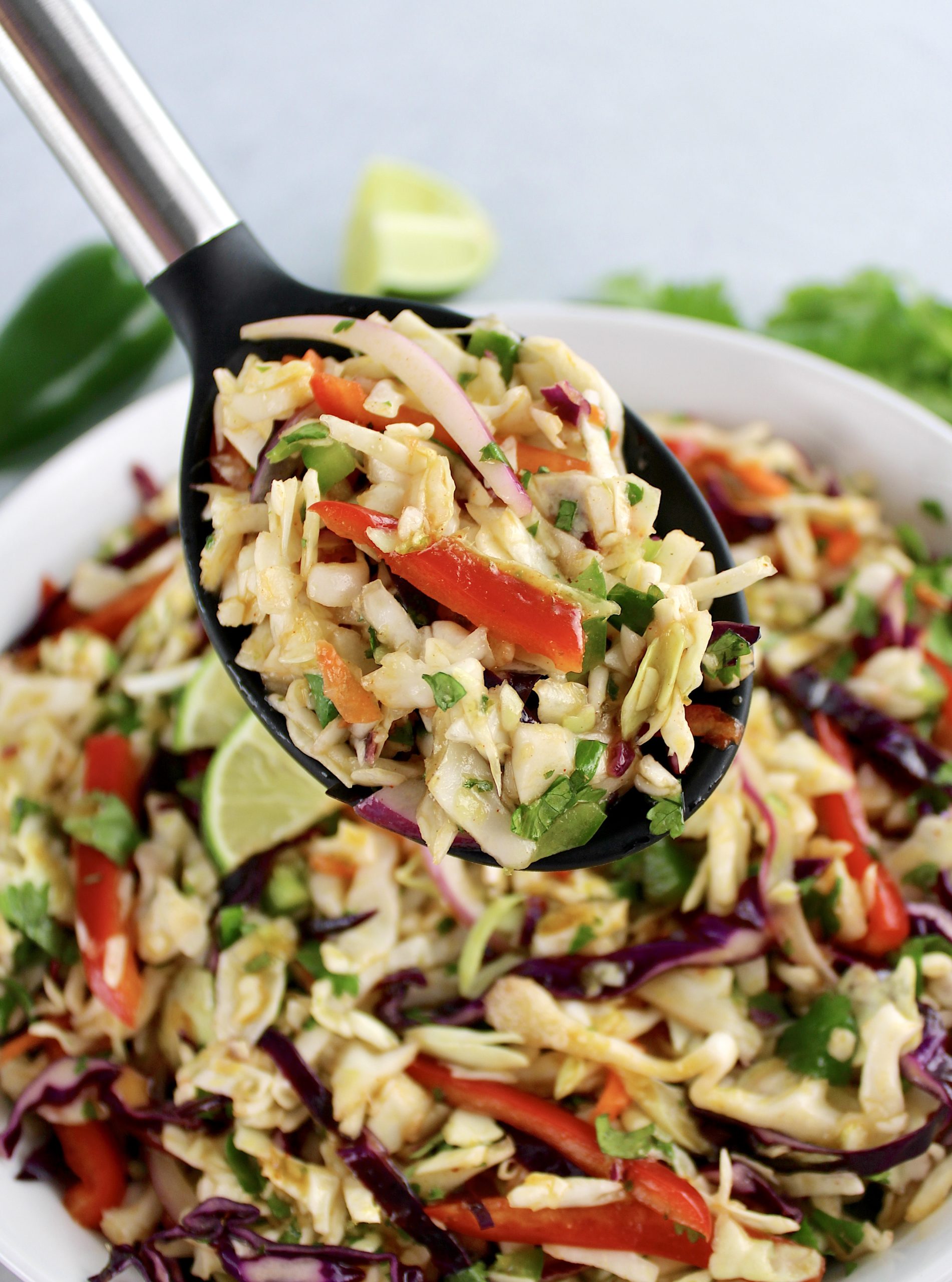 Mexican Coleslaw with black spoon holding up some